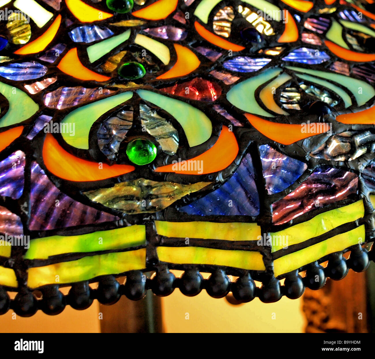 Glasmalerei Lampe Schatten Nahaufnahme mit Perlen auf der Kante sowie orange blau und gelb Designs hat das Gefühl des Art deco Stockfoto