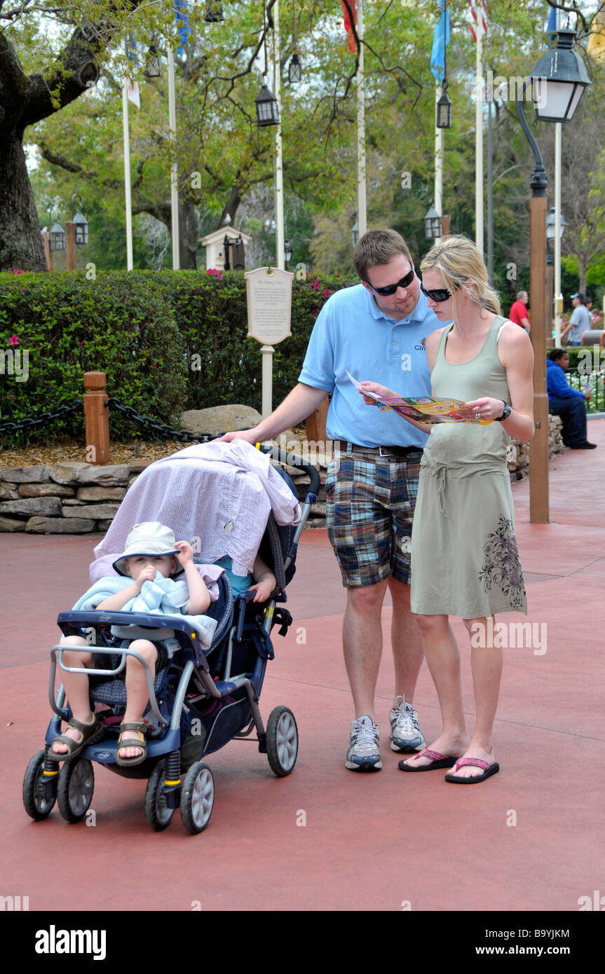 Weiße junges Paar mit Kind und Kinderwagen schauen Sie sich die Karte bei Walt Disney Magic Kingdom Theme Park Orlando Florida zentrale Stockfoto