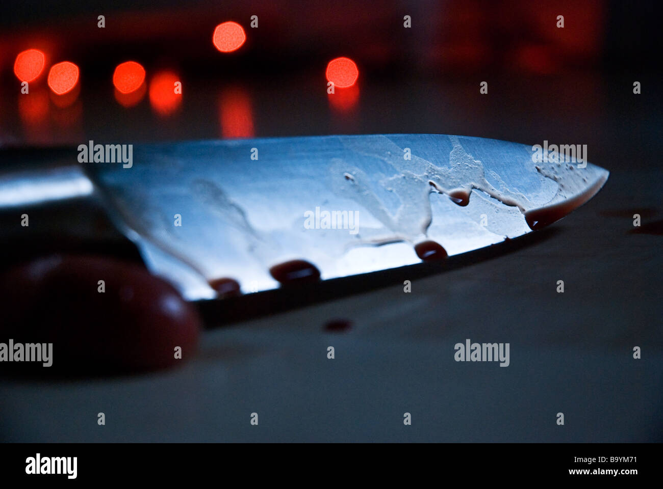 Eine blutige finstere Szene eine Hand und ein Messer auf dem Boden mit roten Lichtern im Hintergrund. Stockfoto