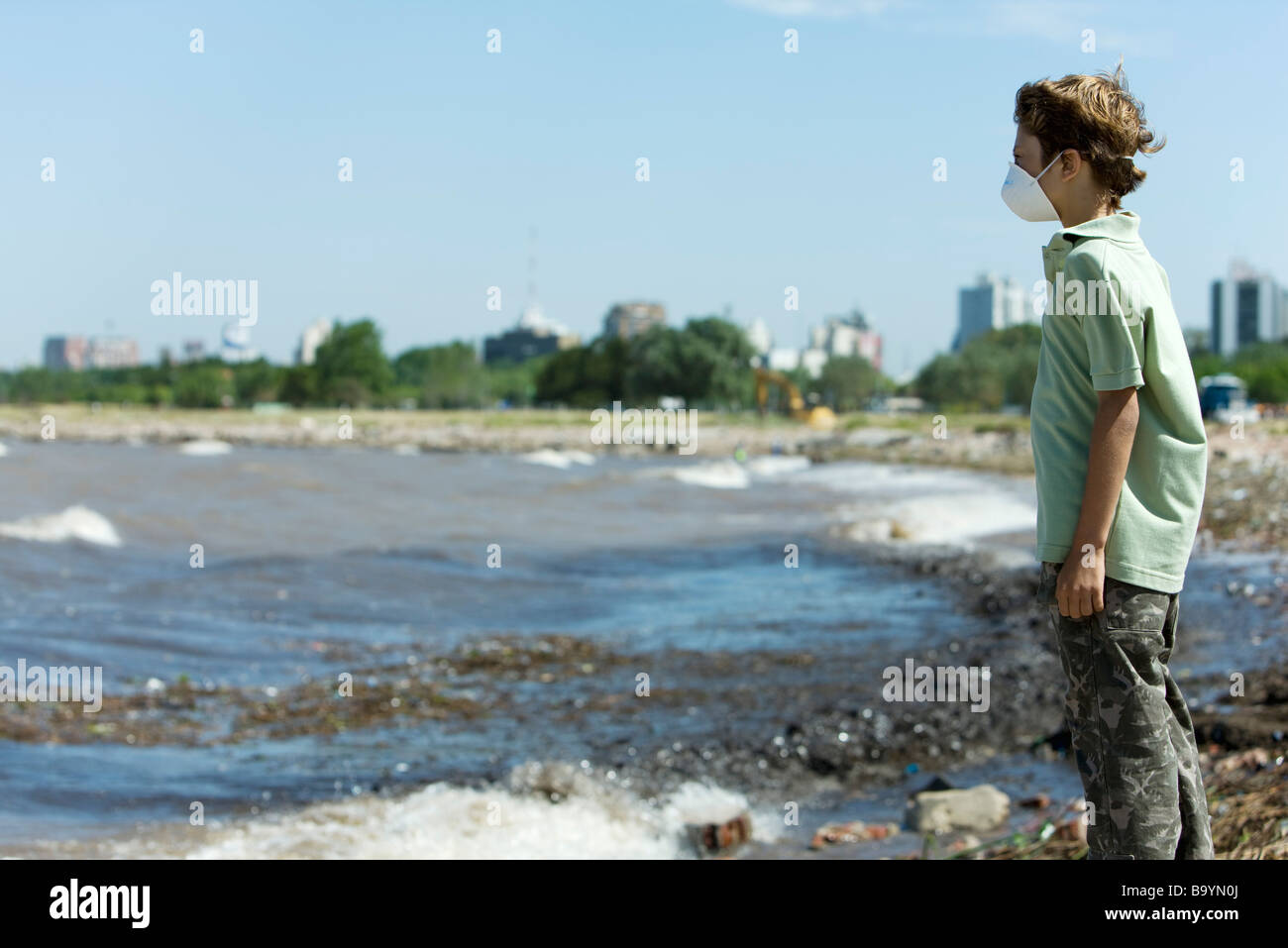 Junge mit Umweltverschmutzung Maske, stehend auf verschmutzten Ufer Stockfoto