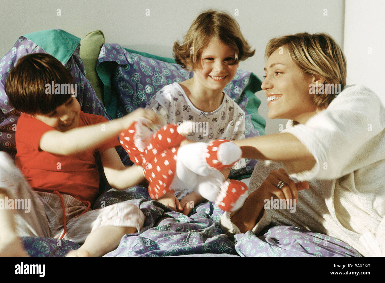 Familie spielt mit Kuscheltier im Bett, Lächeln Stockfoto