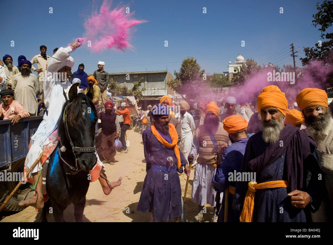Ein junger Nihang/Akali/Sikh auf Pferd wirft Farbe/gulal in der Luft während Holla Mohalla Festivals bei Anandpur Saheb, Punjab, Indien Stockfoto