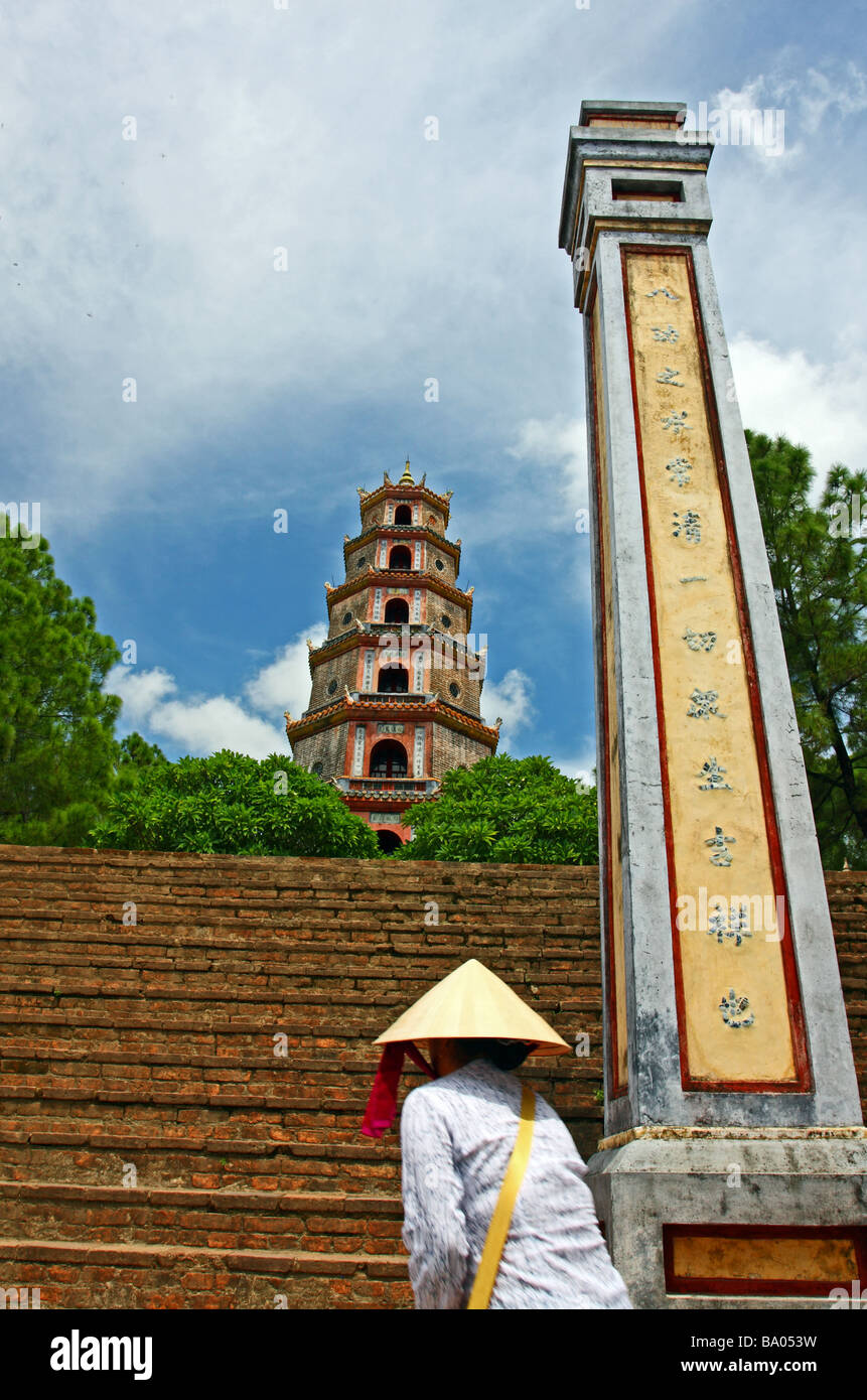 Asian-Denkmal. Thien Mu Pagode mit einer Frau mit dem konischen Hut beim Treppensteigen. Hue, Vietnam Stockfoto