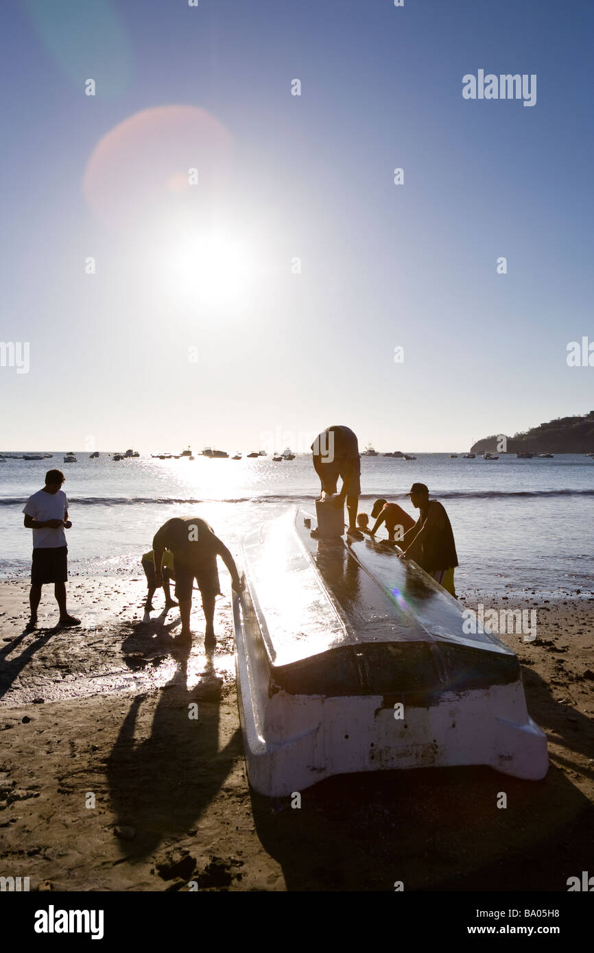 Fischer Reinigung ein Boot am Strand in San Juan del Sur, Nicaragua. Stockfoto