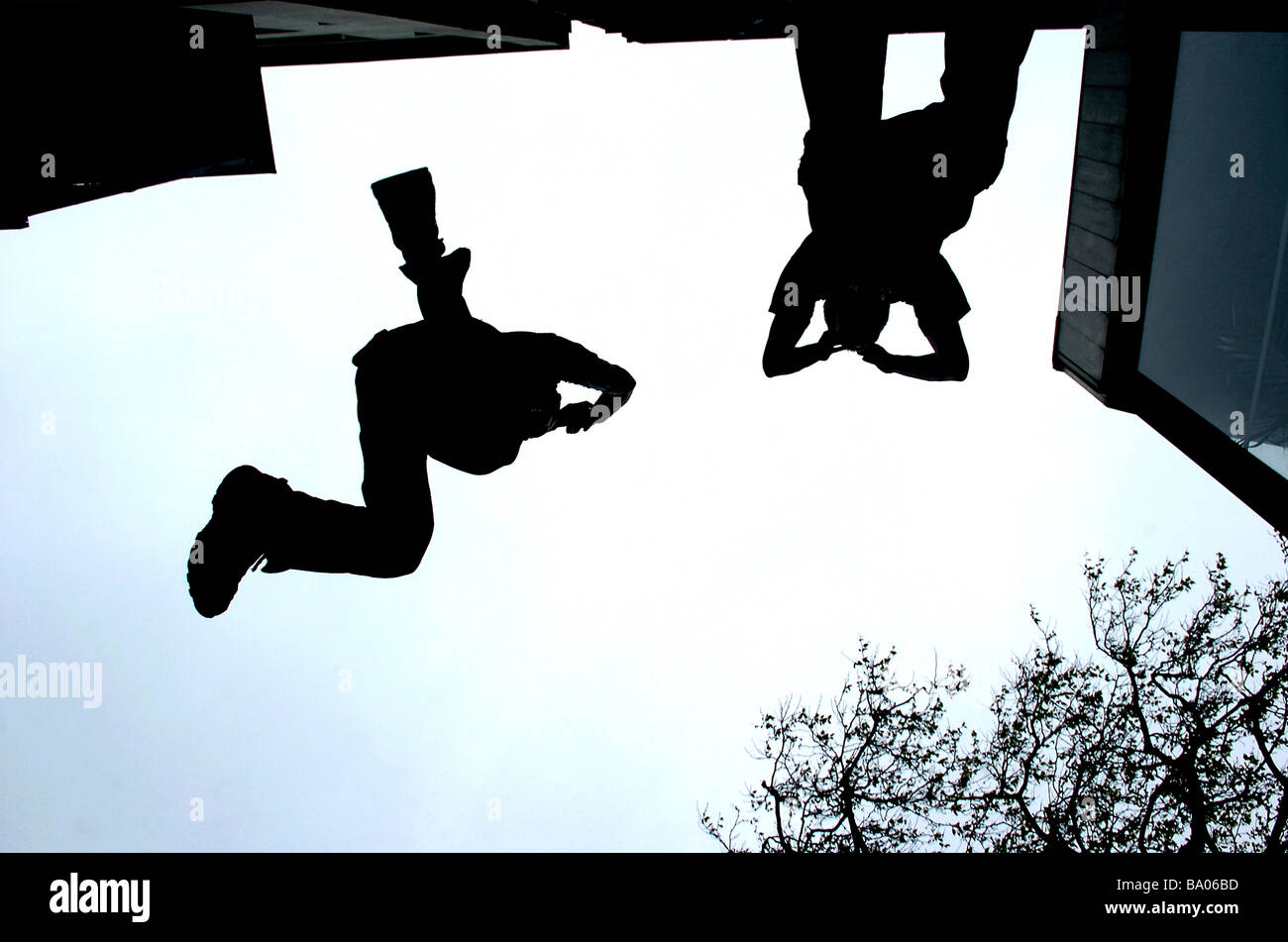 Zwei freie Läufer sind Silhouette, wie sie von einem Gebäude zum anderen springen Stockfoto