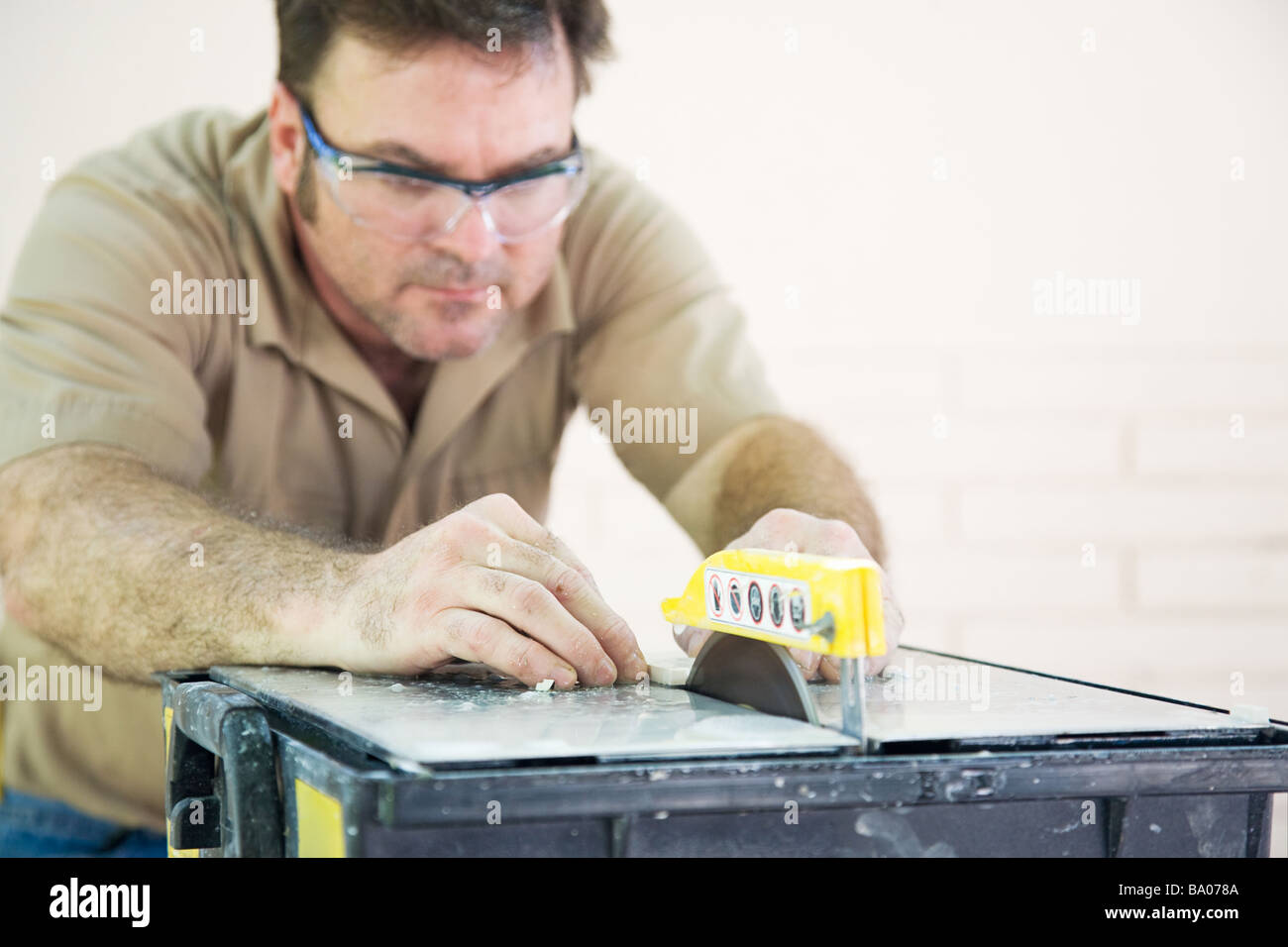 Kachel Arbeitnehmer schneiden Keramikfliesen mit einem Tisch sah geringe Schärfentiefe mit Fokus auf Hände und Klinge Stockfoto