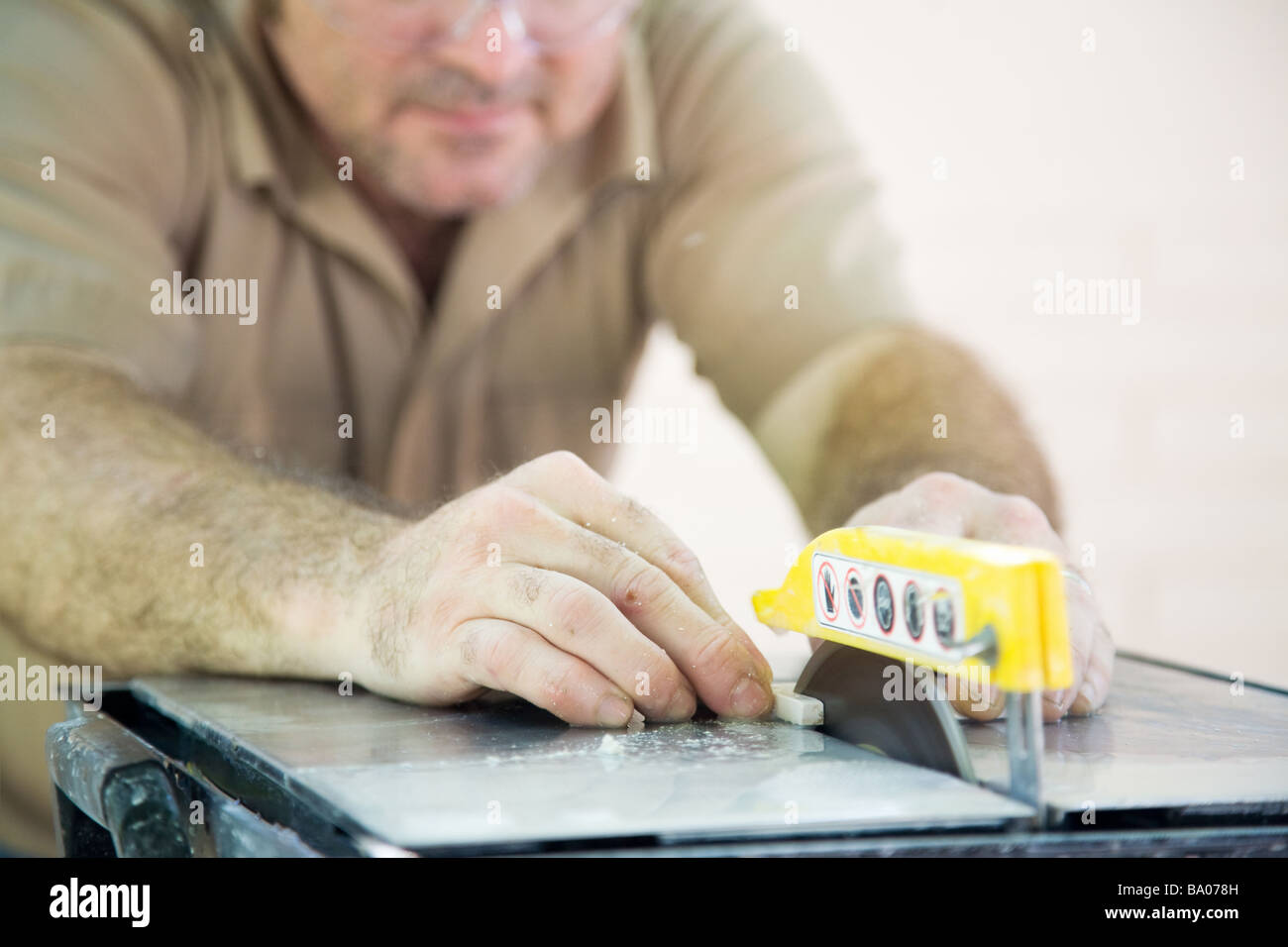 Nahaufnahme eines Kachel Arbeiter s Hände, als er Fliesen mit einer Tischkreissäge schneidet Stockfoto