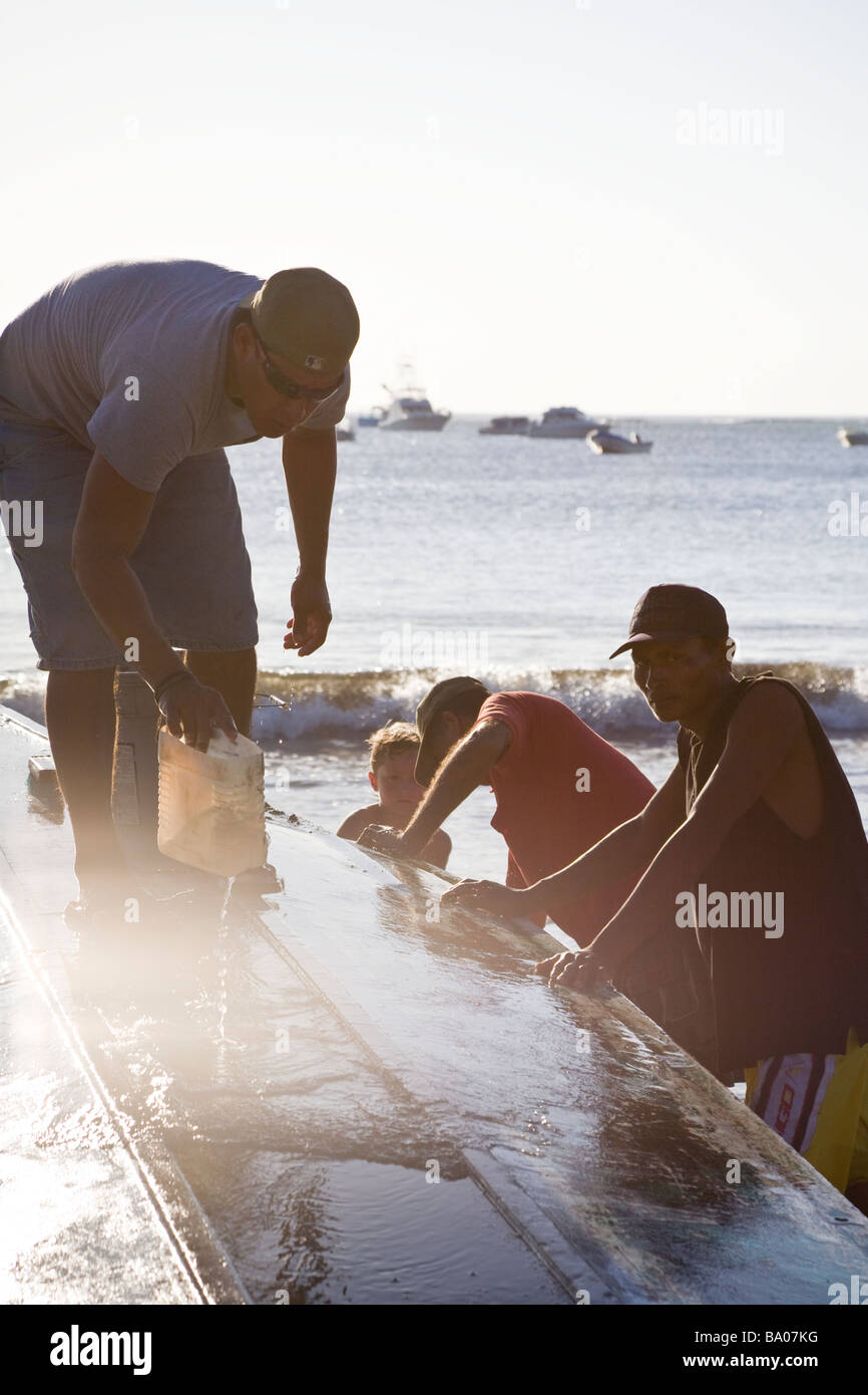 Männer, die Reinigung der Boden eines Bootes am Strand von San Juan del Sur, Nicaragua. Stockfoto
