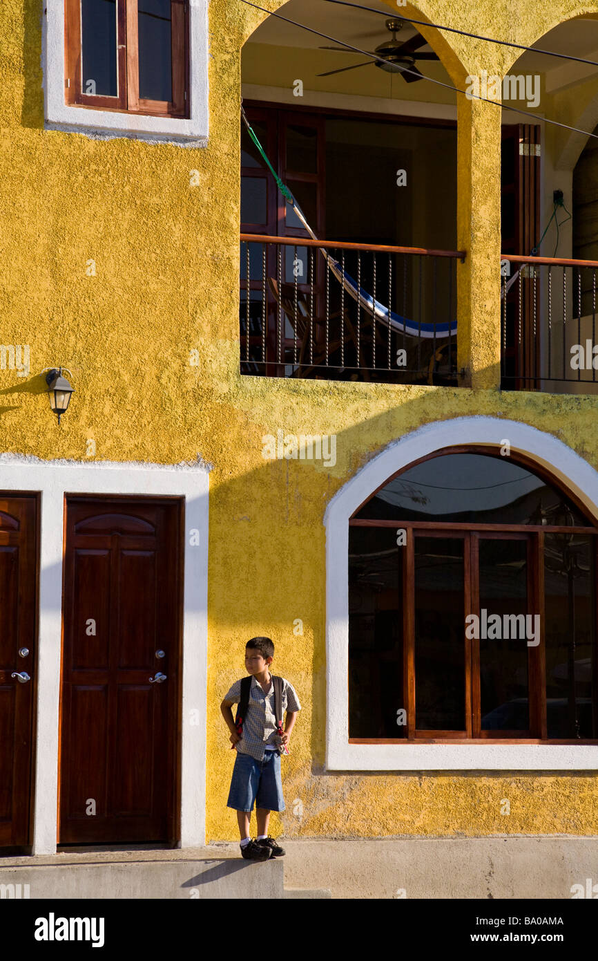 Junge Schuljunge steht man vor einem bunten Gebäude in San Juan del Sur, Nicaragua. Stockfoto