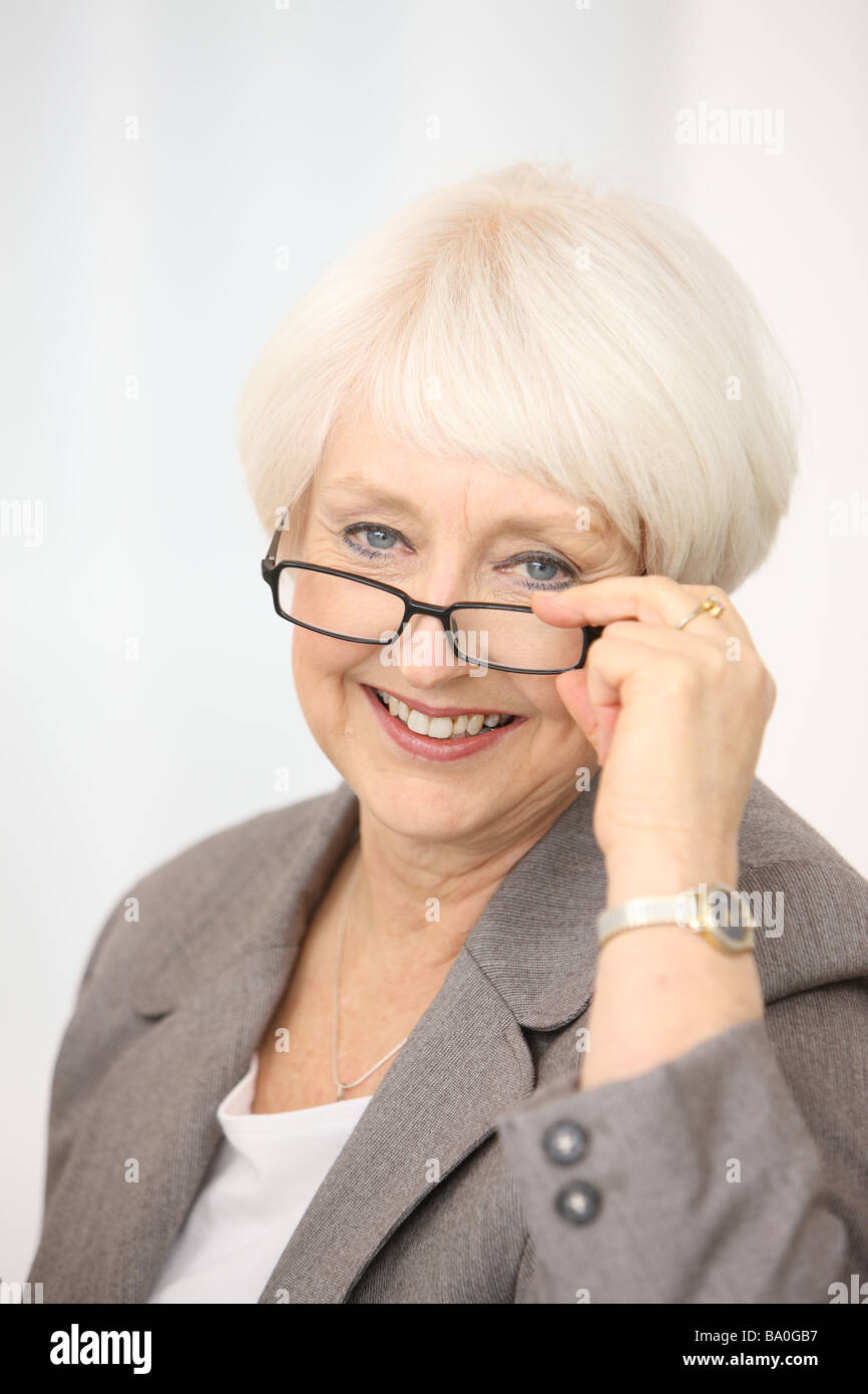 Professionelle senior Geschäftsfrau mit Blick auf Gläser Stockfoto