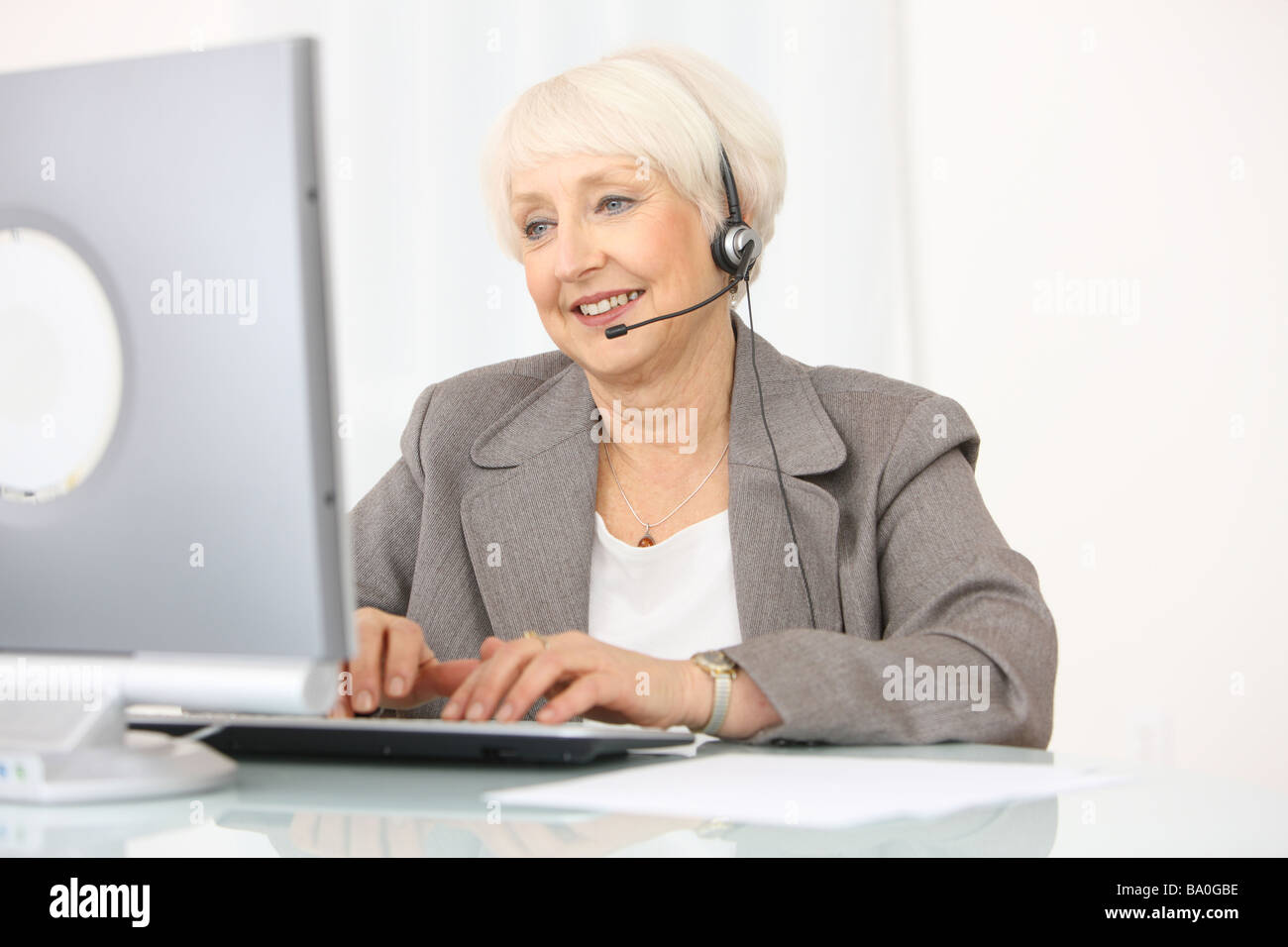 Professionelle senior Geschäftsfrau mit Kopfhörer und computer Stockfoto