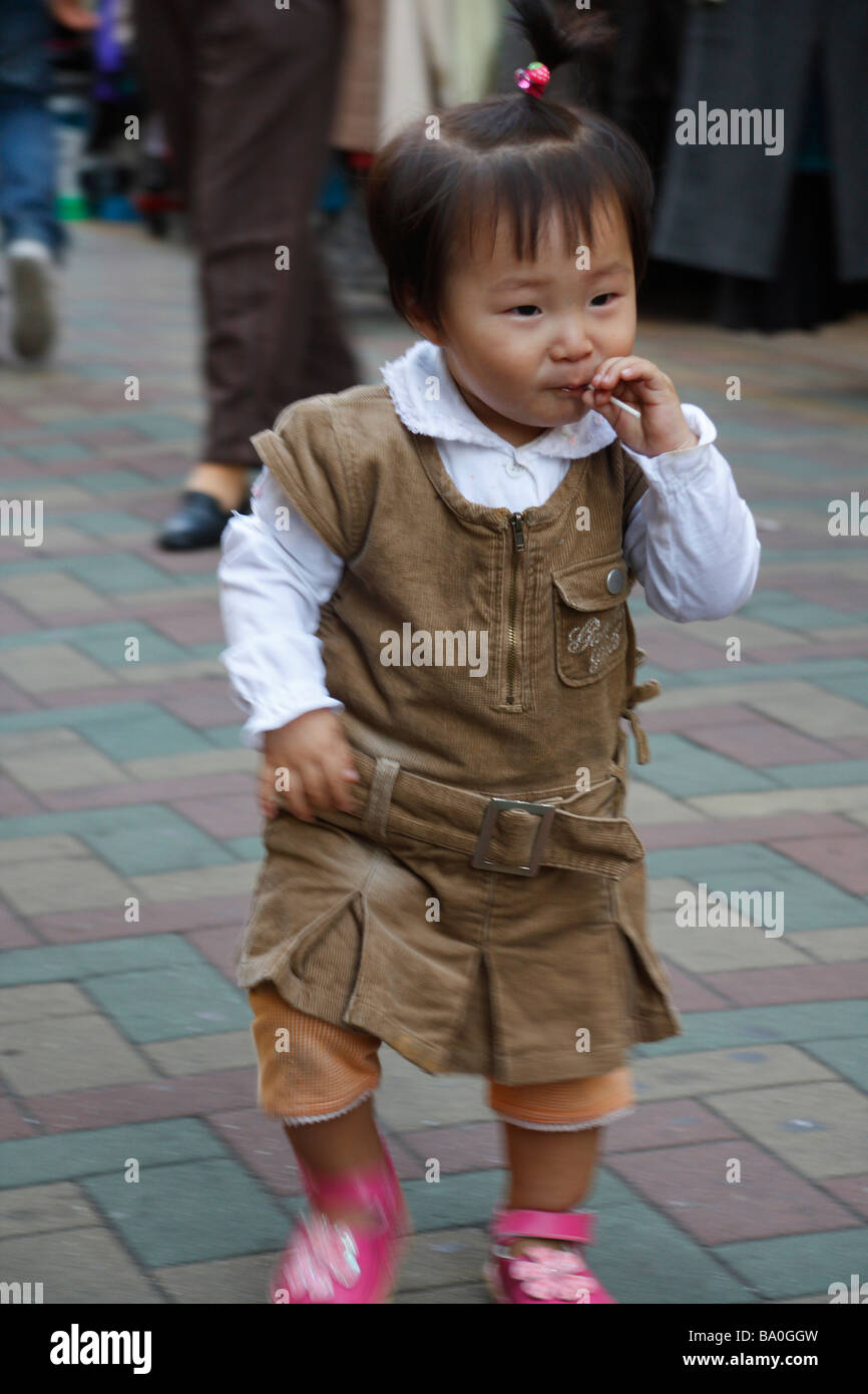 Eine süße junge Koreanerin zu Fuß mitten auf der Straße auf dem Marktplatz in Busan, mit einem Lutscher. Stockfoto