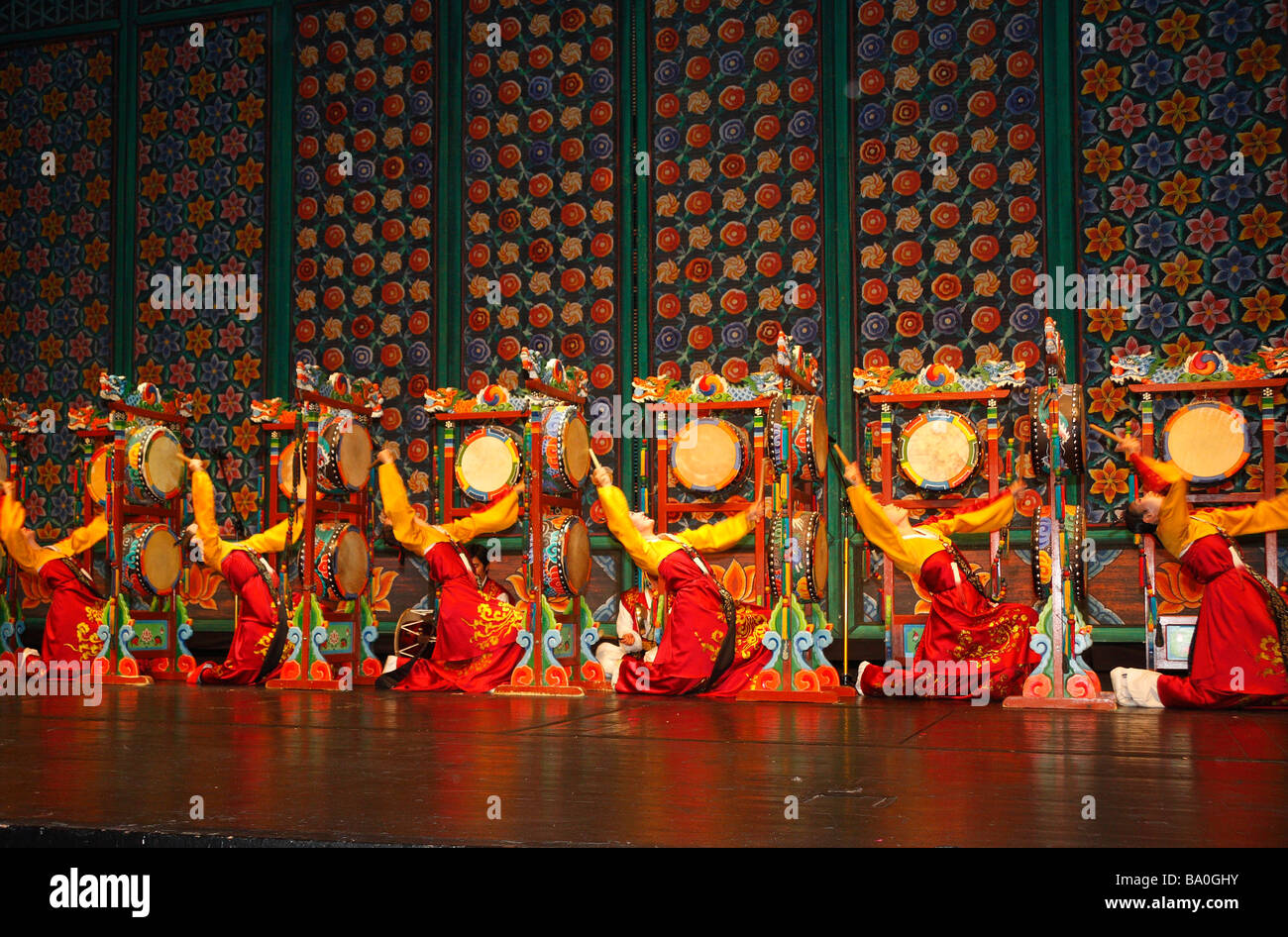 Eine Gruppe von Koreanerinnen in leuchtendem Gelb und rot Kleider auf der Bühne spielen traditionelle Folkore Trommeln "oh-Go-Mu" Stockfoto