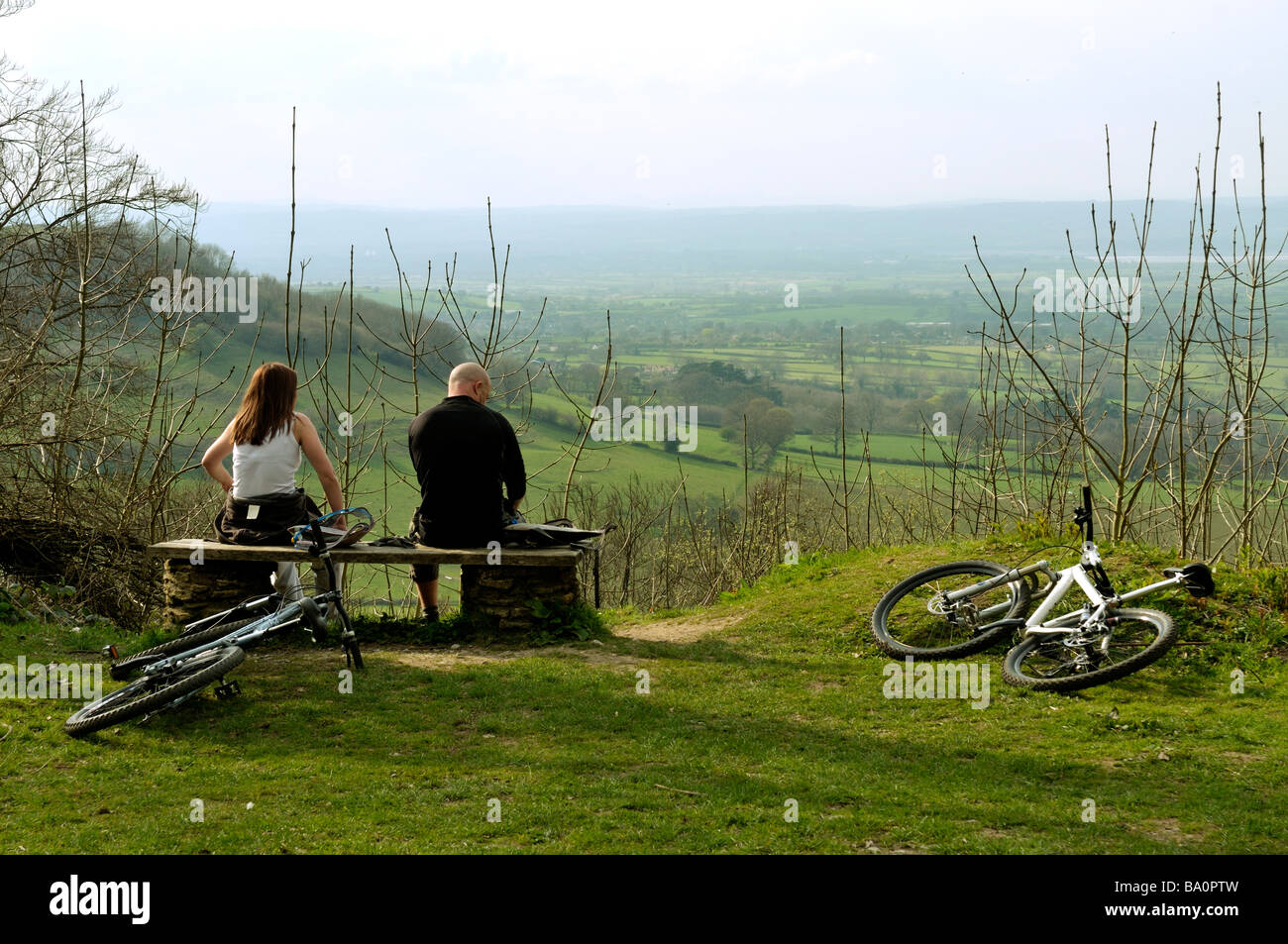 Radfahrer ruhen auf der Bank mit Blick auf Severn Valley von Cotswold Hills im Frühjahr England Stockfoto