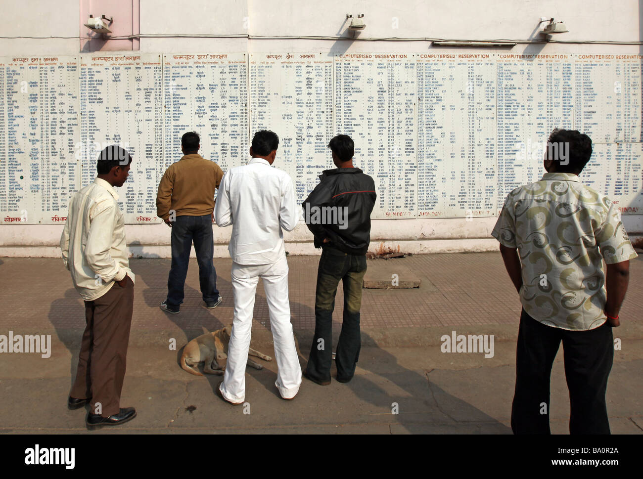 Reisende am Bahnhof New Delhi inspizieren den Zeitplan. Stockfoto