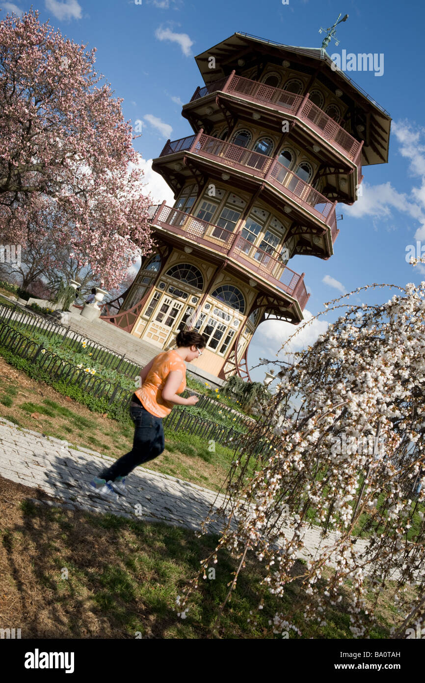 Frau joggt vorbei die Pagode an Patterson Park Frühling Tag Magnolia blühenden Baltimore Maryland Stockfoto