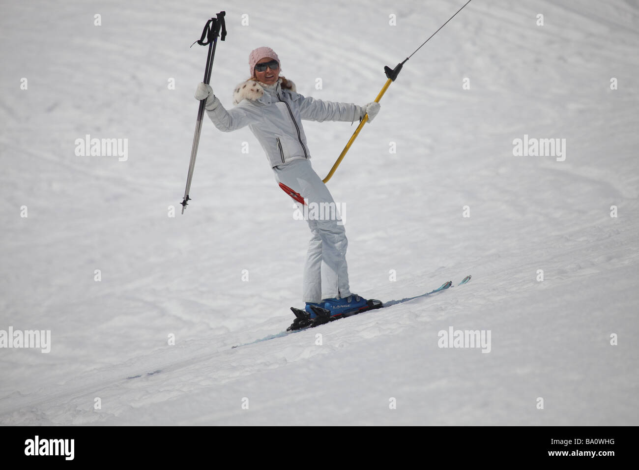 Schöne, weibliche Skifahrer auf einer Schaltfläche Hebebühne im Skigebiet  tragen weiße Skijacke und Hose schwenkten ihre Skistöcke Stockfotografie -  Alamy