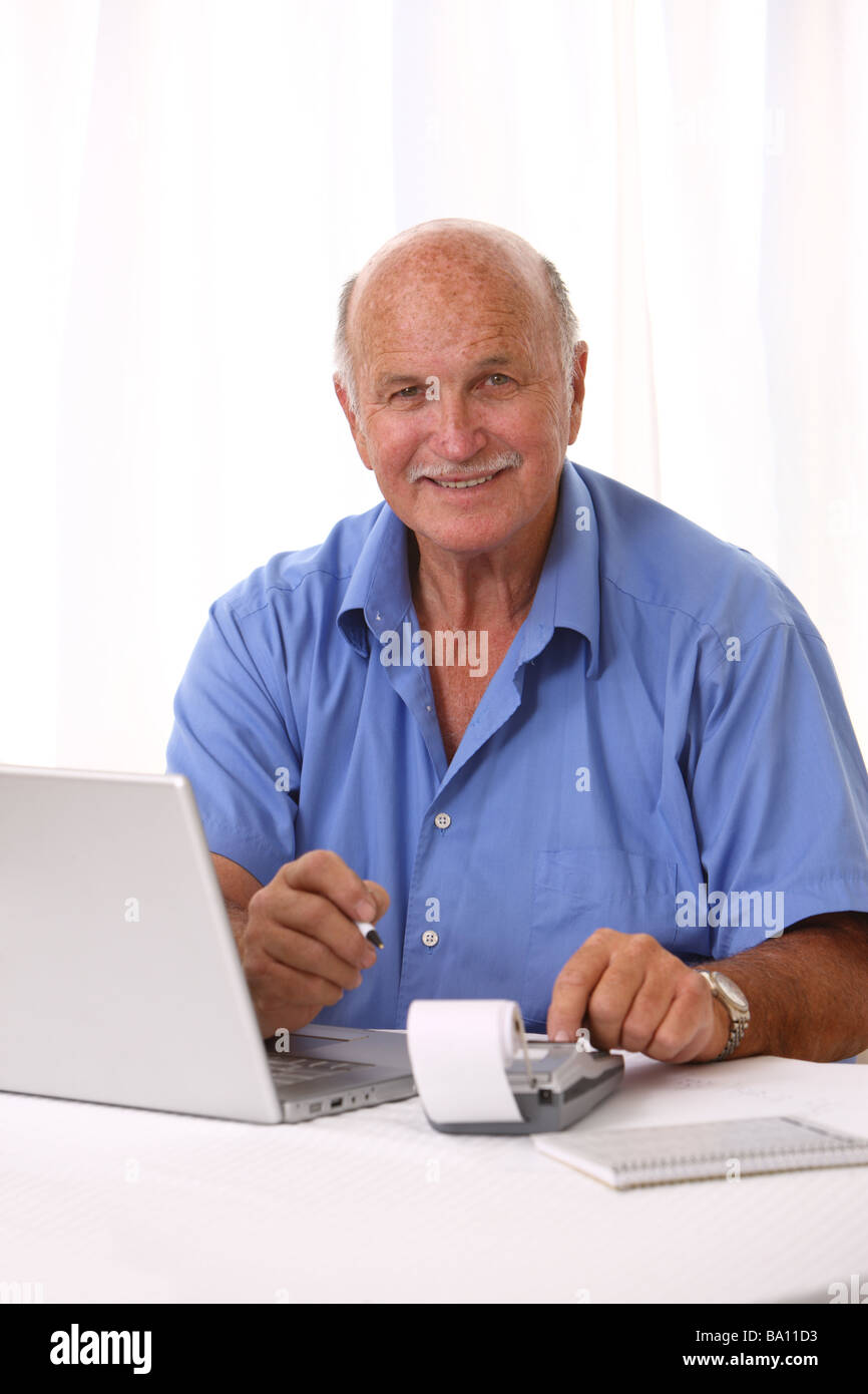 Ältere Mann mit Laptop und Taschenrechner Stockfoto