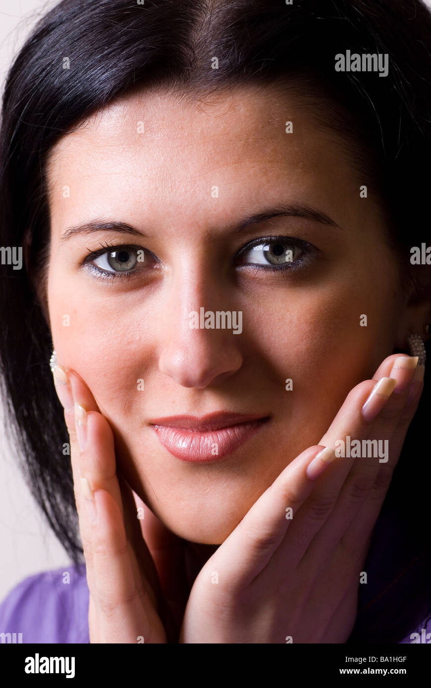 Schöne junge Frau Hände berühren Gesicht Blick in die Kamera Stockfoto