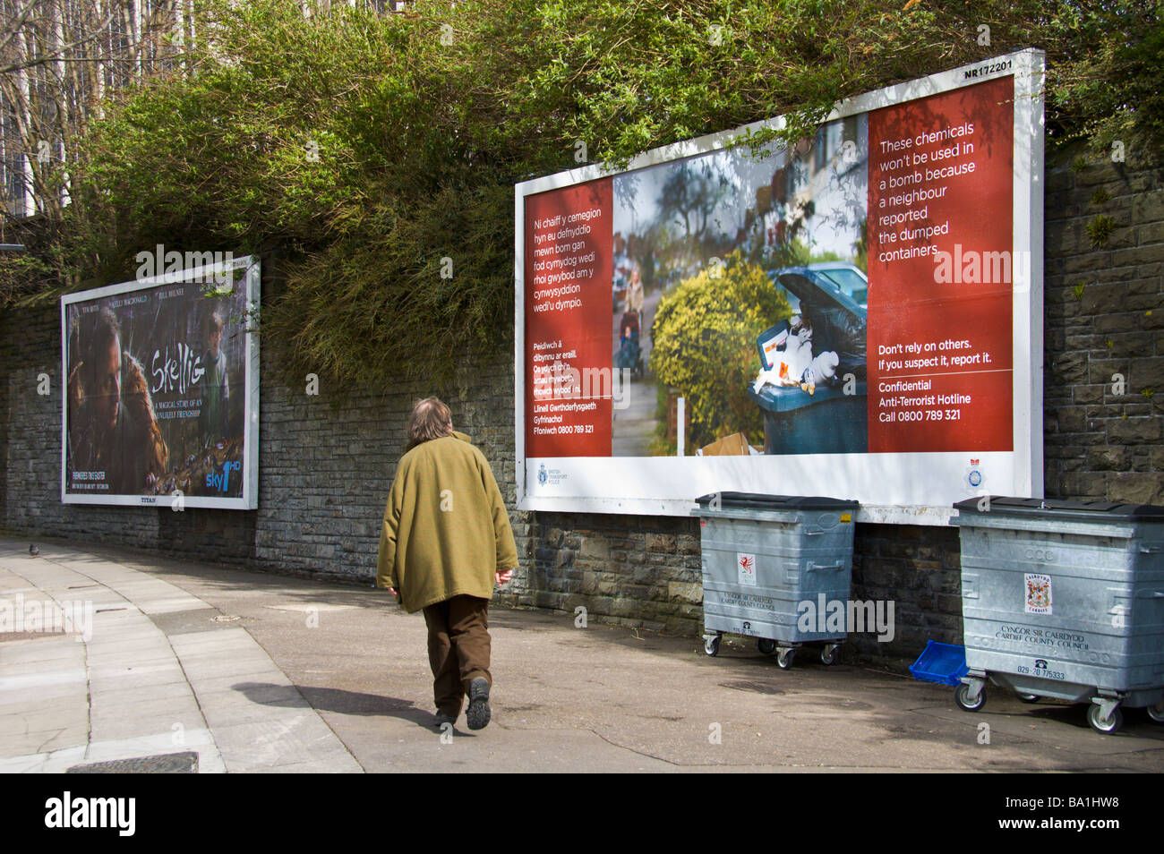 Mann zu Fuß vorbei an Werbung Werbetafeln für Film Skellig auf Sky und British Transport Police an Wand in Cardiff South Wales UK Stockfoto