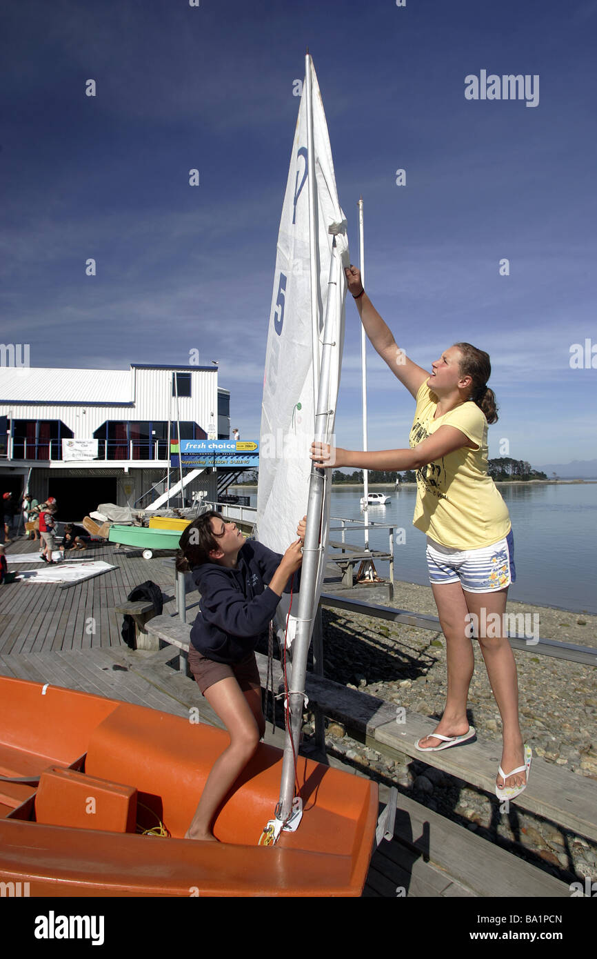 zwei junge Mädchen Matrosen bereiten ein Optimist-Jolle für den Start an Nelson Yacht Club, New Zealand Stockfoto