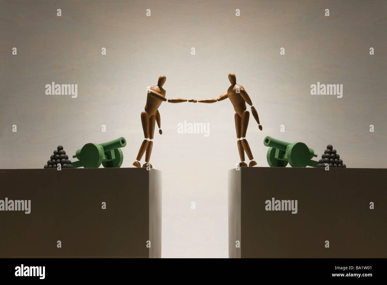 Zwei Figuren schütteln sich die Hände über einen Spalt hat jede Figur eine Kanone im Hintergrund Stockfoto
