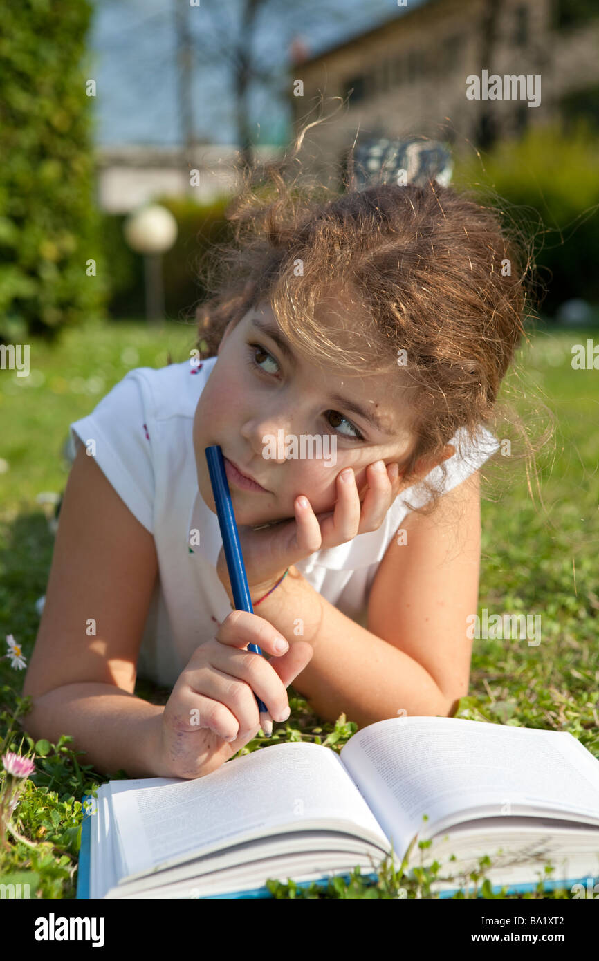Junge Studentin, die ihre Hausaufgaben im Garten Stockfoto