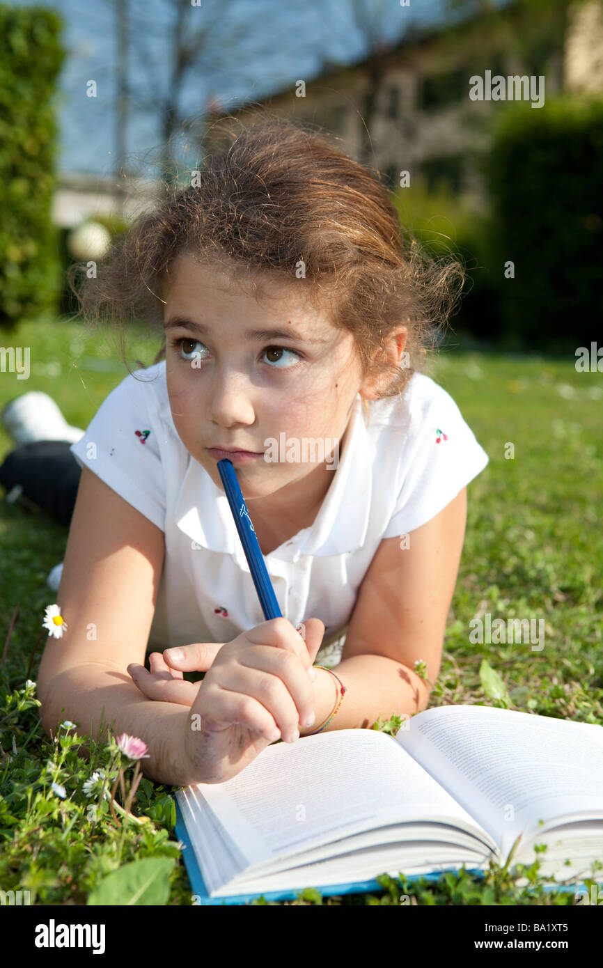 Junge Studentin, die ihre Hausaufgaben im Garten Stockfoto