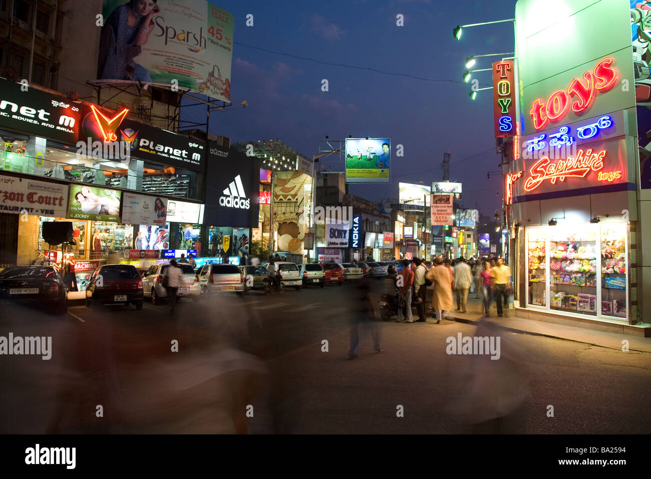 Abend auf Brigade Road im Zentrum von Bangalore, Indien. Fassaden mit Handelsnamen und Werbung Werbetafeln. Stockfoto