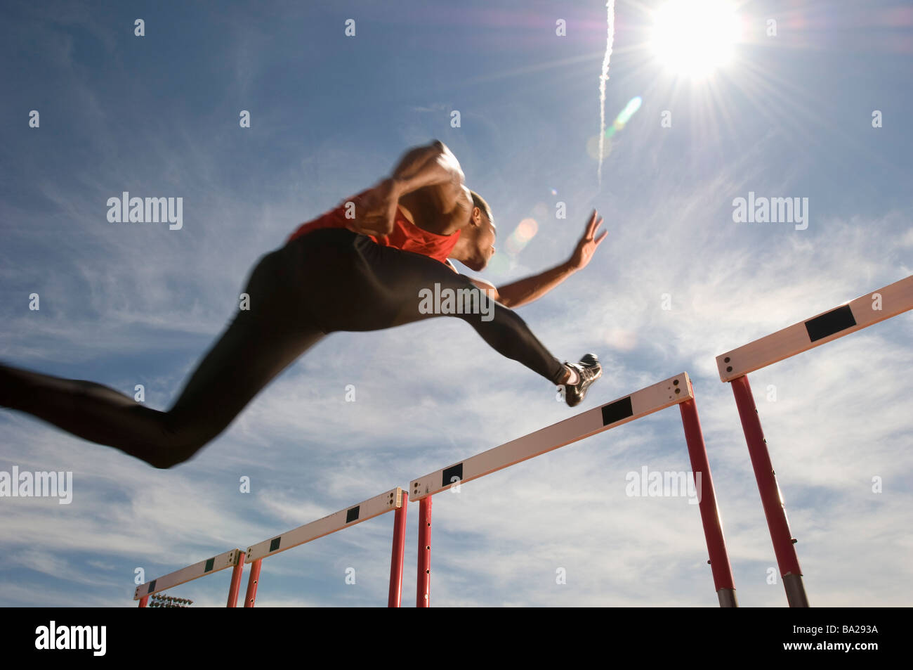 Läufer, die einen Sprung über die Hürde, niedrigen Winkel Ansicht ausführen Stockfoto