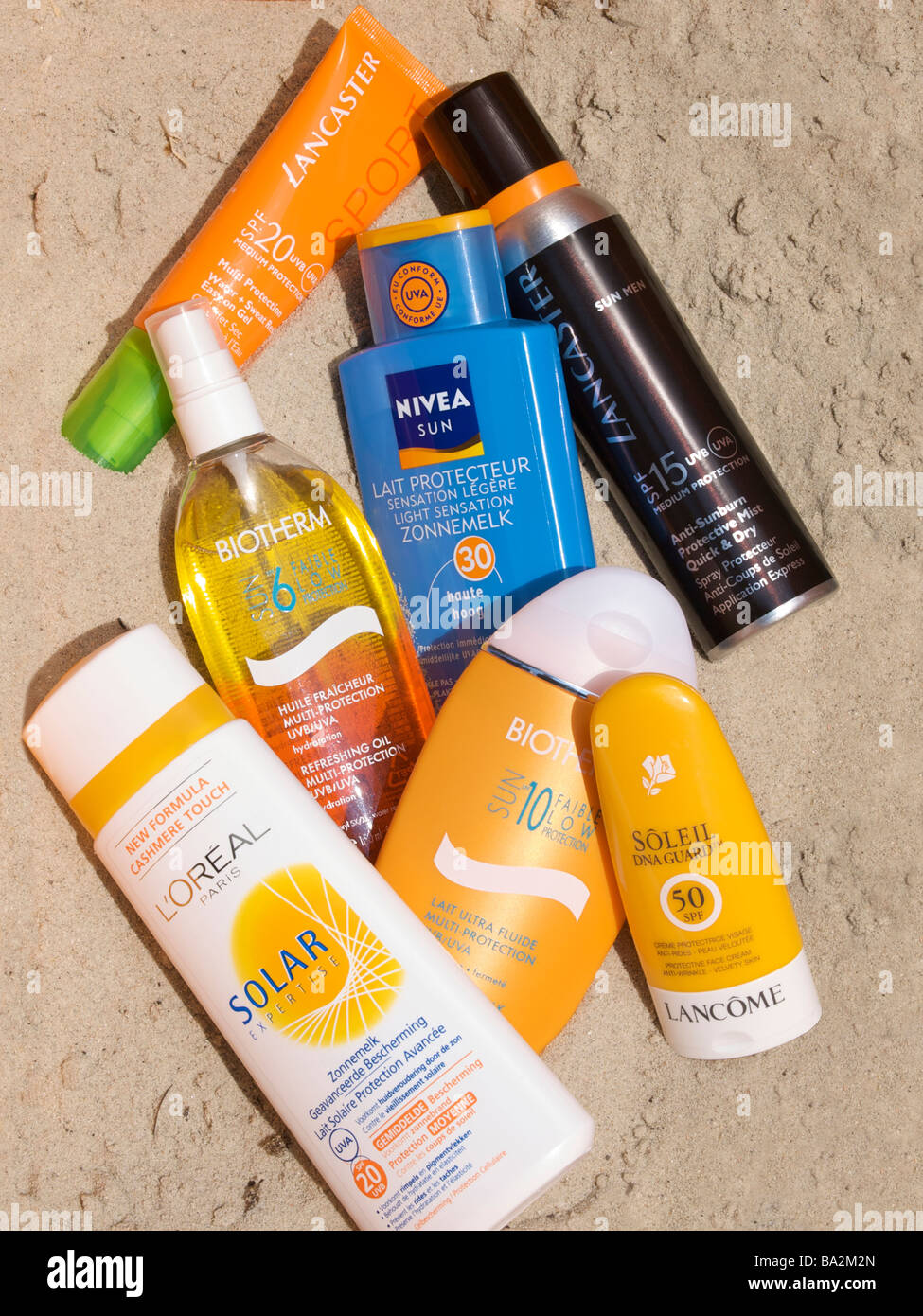 Verschiedenen Sonne Schutz Creme Hautpflege-Produkte im Sand durch echtes Sonnenlicht beleuchtet Stockfoto