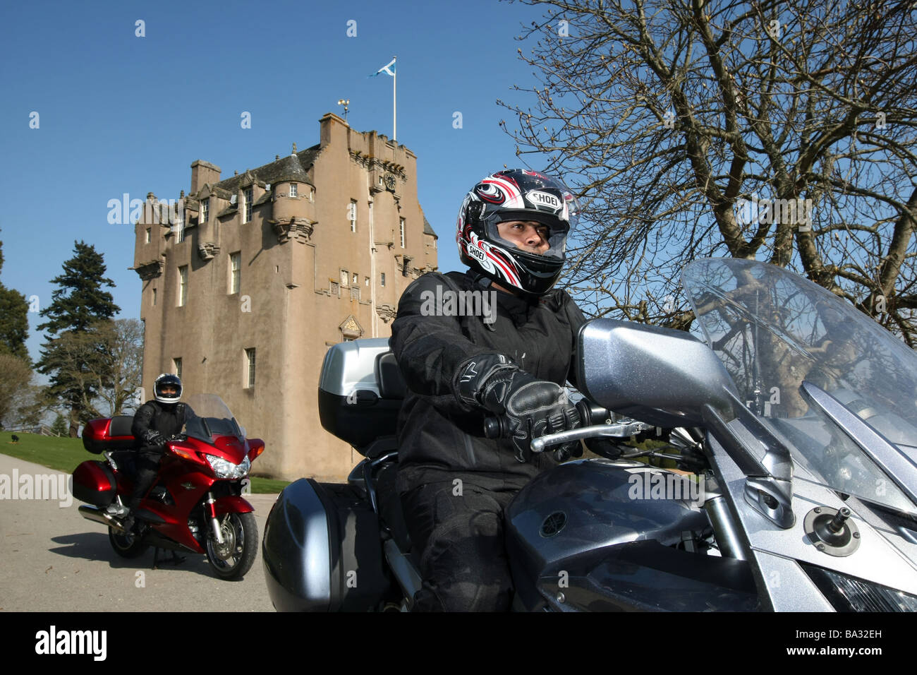 Männliche Motorradfahrer pass ein Schloss in Schottland, Großbritannien im Sommer bei schönem Wetter Stockfoto