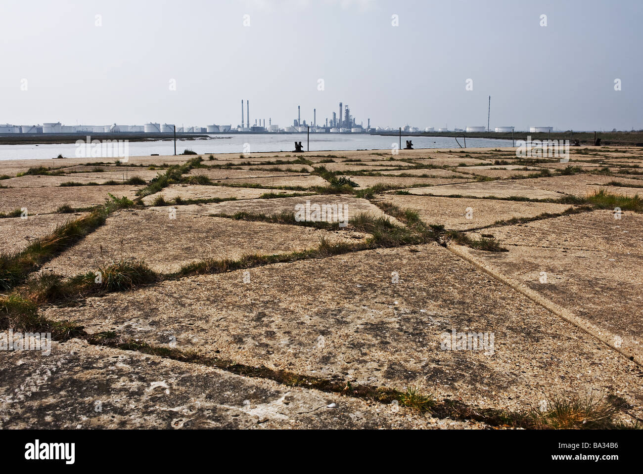 Eine verlassene Steg mit einer Ölraffinerie bei "Holehaven Creek" auf Canvey Island in Essex. Stockfoto