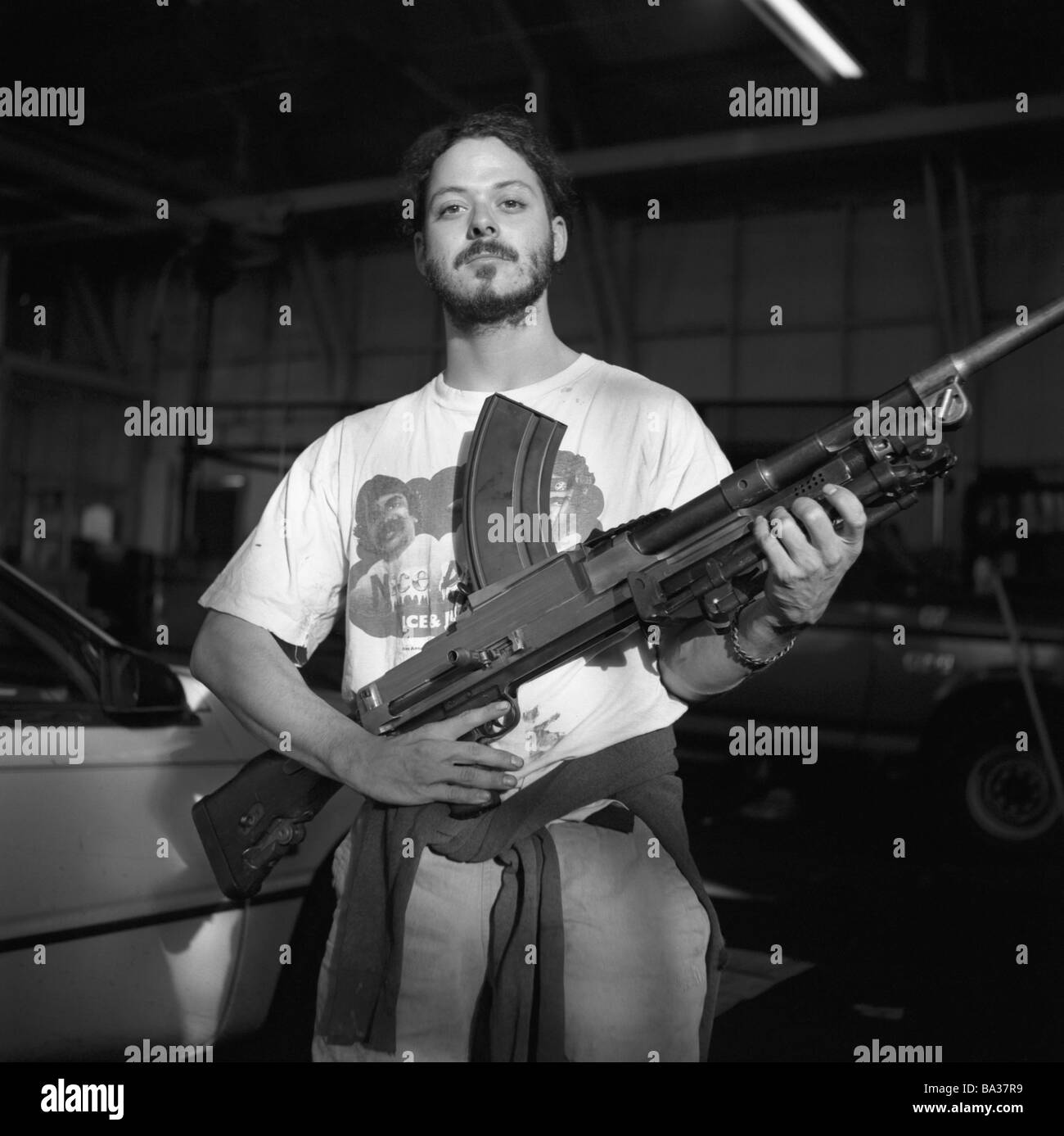 S/w Leute Garage Mann jungen Maschinengewehr Pose garage Werkstatt Halle Lager Autos Pkw Gangster Mafia terroristische Verbrechen Stockfoto