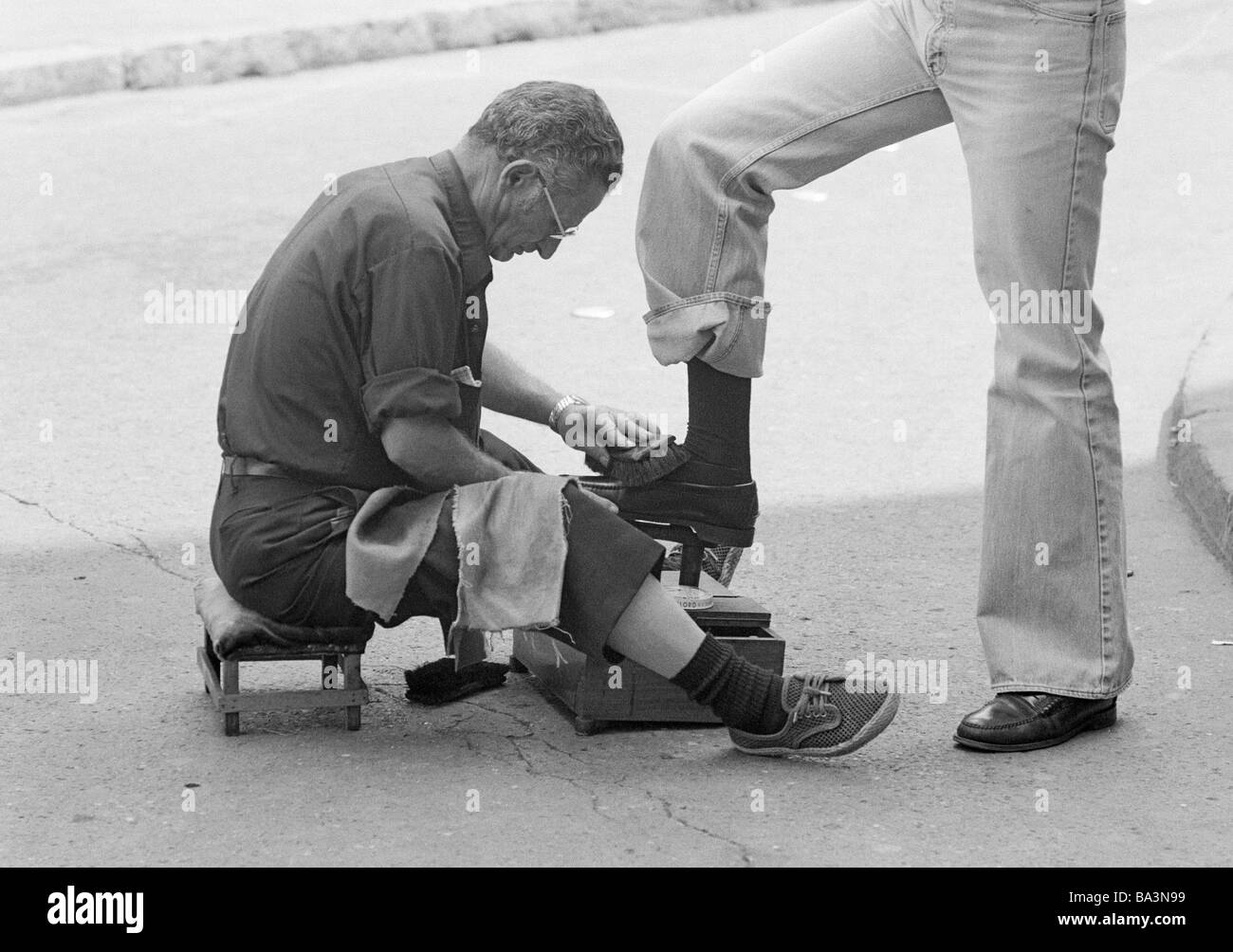 70er Jahre, schwarz / weiß Foto, Menschen, Business, Shoeblack sitzt auf einem Taboret Polieren Schuhe, im Alter von 50 bis 60 Jahre, Spanien, Valencia Stockfoto