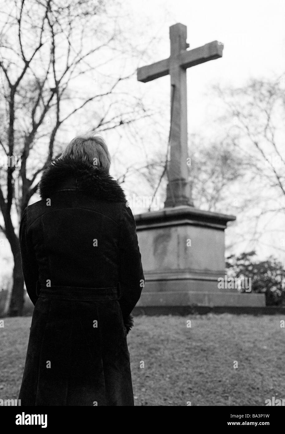 70er Jahre, schwarz / weiß Foto, Menschen, Tod, Trauer, Friedhof, junge Frau steht vor einem Denkmal Kreuz, im Alter 25 bis 30 Jahren, Monika Stockfoto