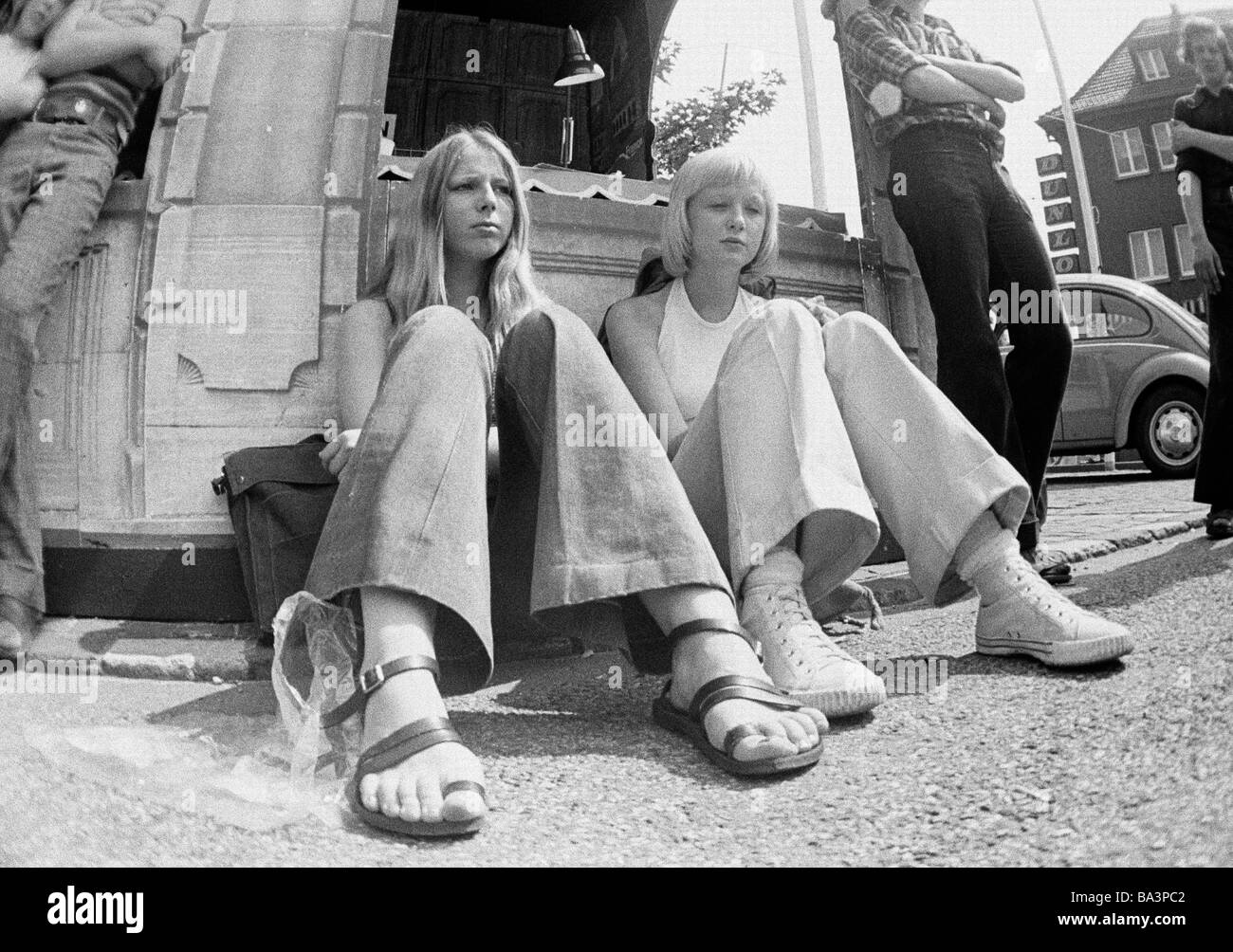 70er Jahre, schwarz / weiß Foto, Menschen, zwei junge Mädchen sitzen am Straßenrand, Stiefel, Hosen, Sandalen, Leinenschuhe, Hose, im Alter von 16 bis 18 Jahre Stockfoto