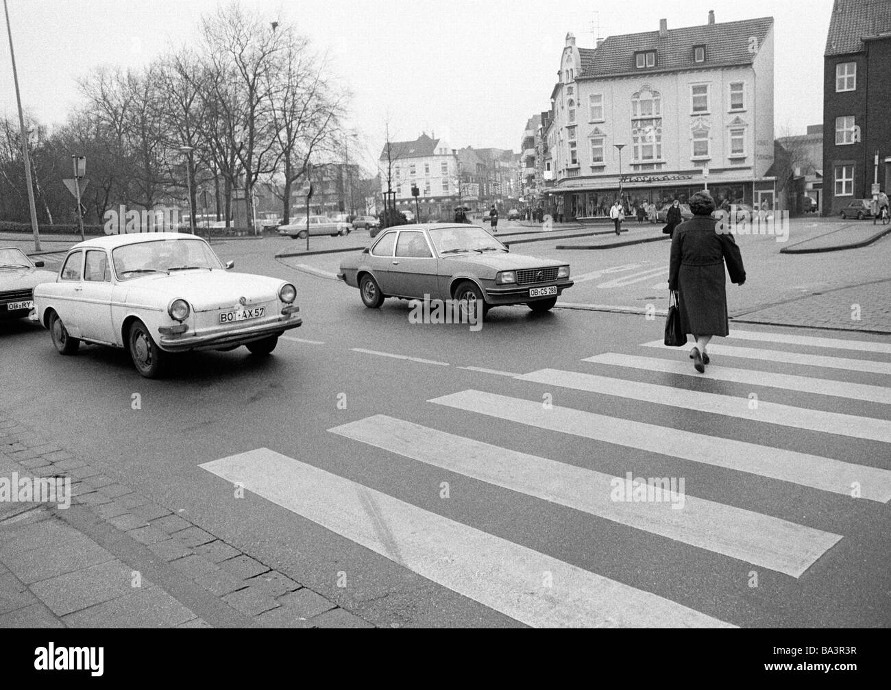 Achtziger Jahre, schwarz / weiß Foto, Straßenverkehr, ältere Frau kreuzt die Straße auf einem Cebra überqueren, wartenden Autos, D-Oberhausen, Nordrhein-Westfalen, Ruhrgebiet, D-Oberhausen-Sterkrade Stockfoto