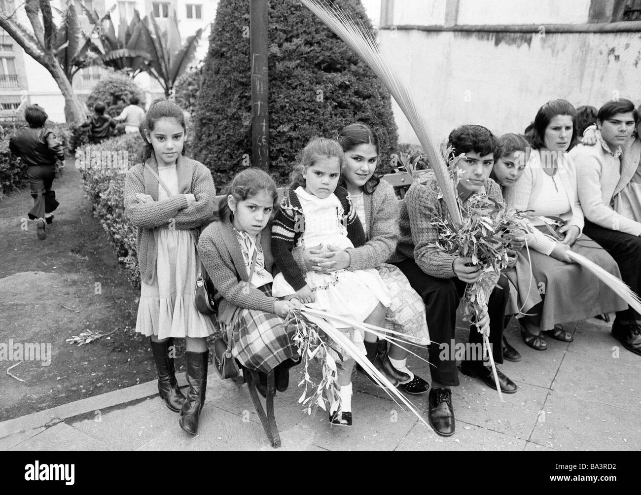 Achtziger Jahre, schwarz / weiß Foto, Ostern, Karwoche, Palmsonntag 1981, Kirche Parade, Familien mit vielen Kindern sitzen auf einer Bank holding Palmzweige in den Händen, Mann, im Alter von 40 bis 45 Jahre, Mann, im Alter von 35 bis 40 Jahre, junge, im Alter von 13 bis 16 Jahre, fünf Mädchen im Alter von 4 bis 14 Jahre, Spanien, Kanarische Inseln, Kanaren, Teneriffa, La Orotava Stockfoto