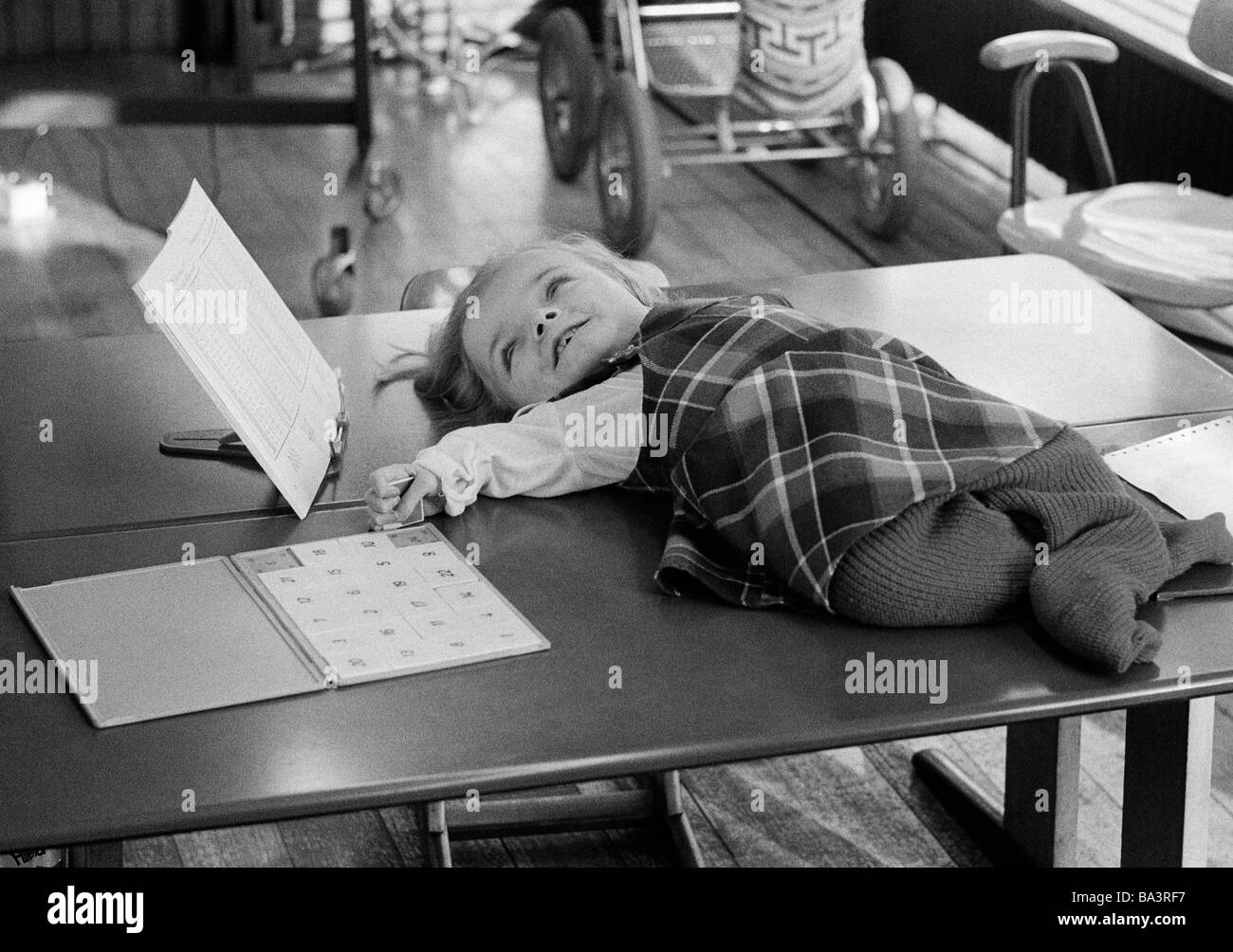 70er Jahre, schwarz / weiß Foto, Menschen, körperlicher oder geistiger Behinderung, Unterricht, Schülerin liegt auf einem Tisch und liest in einem Schulheft, im Alter von 4 bis 8 Jahre, Carola, spezielle Schule Alsbachtal, D-Oberhausen, D-Oberhausen-Sterkrade, Ruhrgebiet, Nordrhein-Westfalen Stockfoto