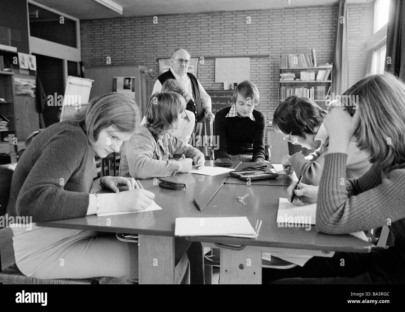 Der siebziger Jahre, schwarz / weiß Foto, Menschen, körperlicher oder geistiger Behinderung, Schulunterricht, Klassenlehrer betreut Schüler und SchülerInnen während einer Klassenarbeit, auch Trainee sitzt da, im Alter von 60 bis 70 Jahren, im Alter von 14 bis 18 Jahre, Willi, spezielle Schule Alsbachtal, D-Oberhausen, D-Oberhausen-Sterkrade, Ruhrgebiet, Nordrhein-Westfalen Stockfoto