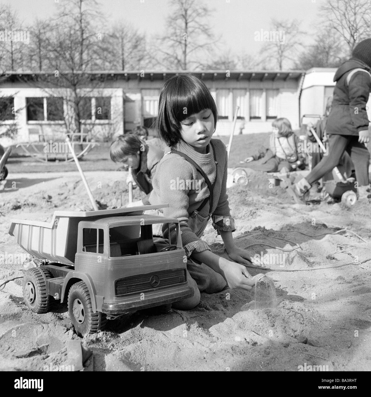 70er Jahre, schwarz / weiß Foto, Menschen, körperlicher oder geistiger Behinderung, Schule, Studienpause, Schulhof, jungen aus Vietnam spielt mit einem Spielzeugauto in einem Sandkasten im Alter von 6 bis 10 Jahre, Tan, spezielle Schule Alsbachtal, D-Oberhausen, D-Oberhausen-Sterkrade, Ruhrgebiet, Nordrhein-Westfalen Stockfoto