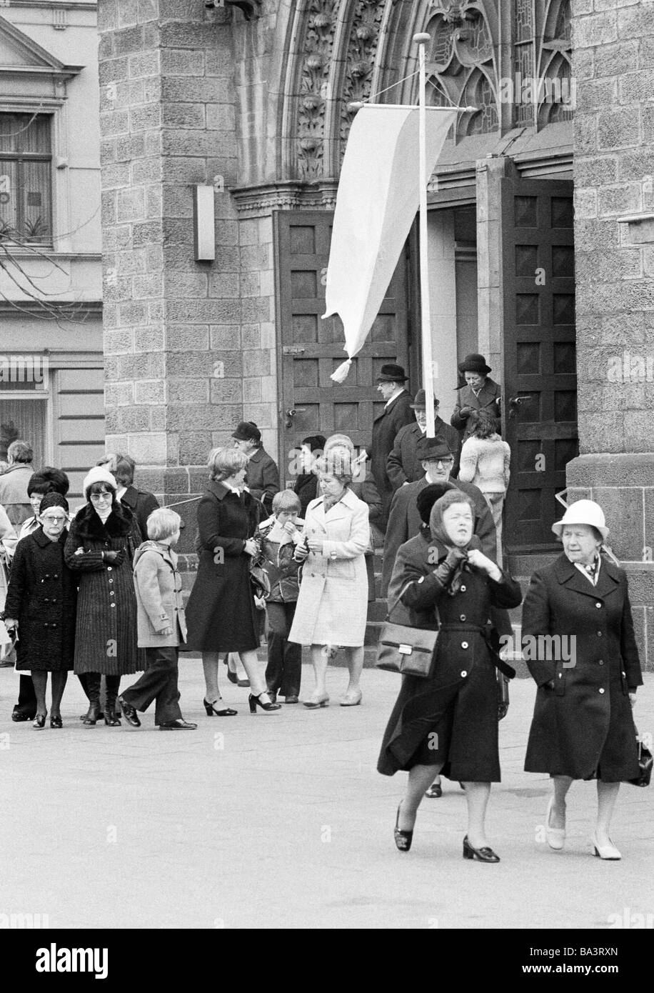 70er Jahre, schwarz / weiß Foto, Religion, Christentum, Kirchgängern verlassen der Kirche nach dem Gottesdienst, Kirchenportal, Flagge Stockfoto