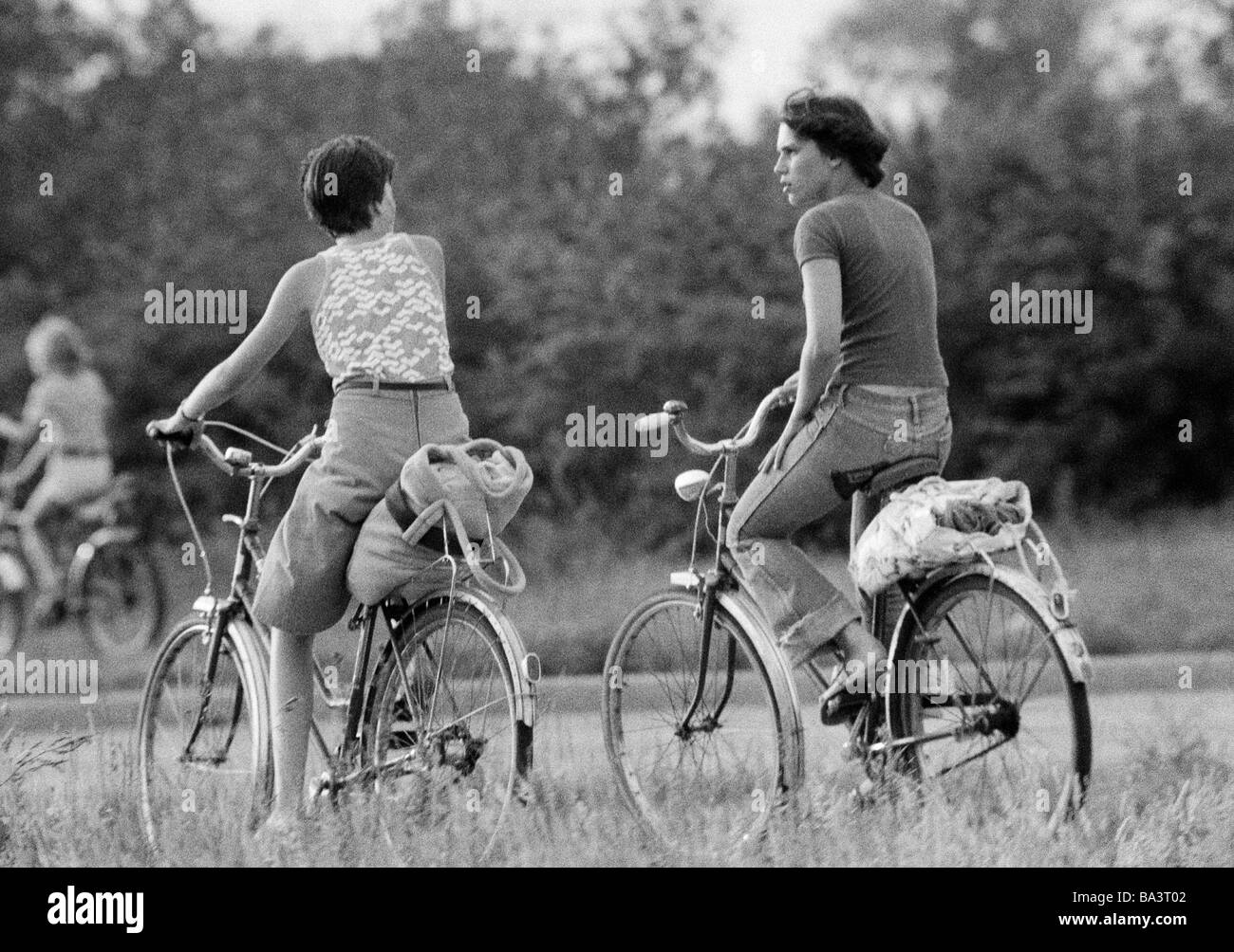 70er Jahre, schwarz / weiß Foto, Menschen, zwei junge Mädchen auf Fahrrädern machen eine Vergnügungsreise, Utensilien am Koffer Rack, Stiefel, Rock, Jeans Hosen, im Alter von 18 bis 22 Jahre Stockfoto