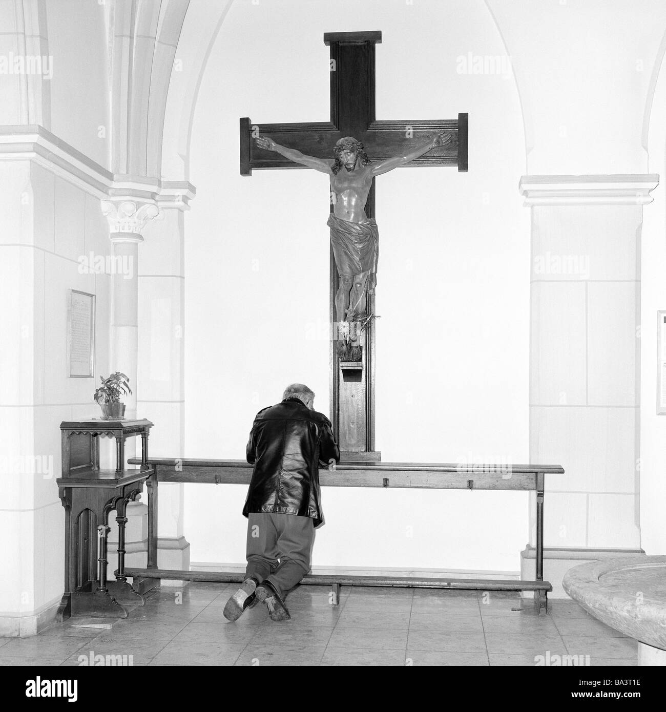 Schwarz / weiß Foto, Religion, Christentum, der siebziger Jahre älterer Mann in einer Kirchenbank kniet und betet unter dem Kreuz, im Alter von 55 bis 70 Jahren, Paul Stockfoto