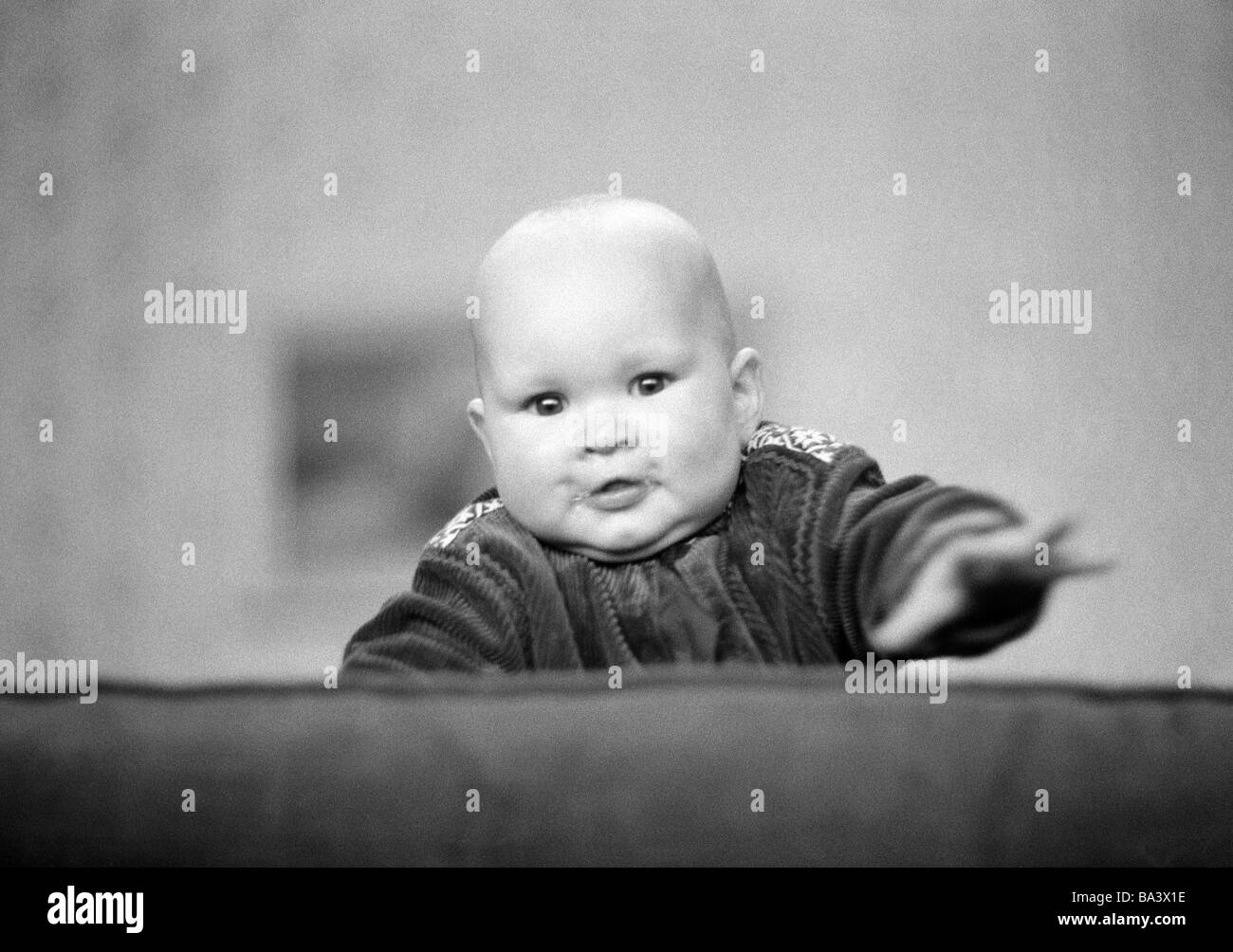 70er Jahre, schwarz / weiß Foto, Menschen, Kinder, Baby versucht zu erklimmen die Rückenlehne der Couch, im Alter von 6 bis 12 Monaten, im Alter von 1 Jahr, Christina Stockfoto