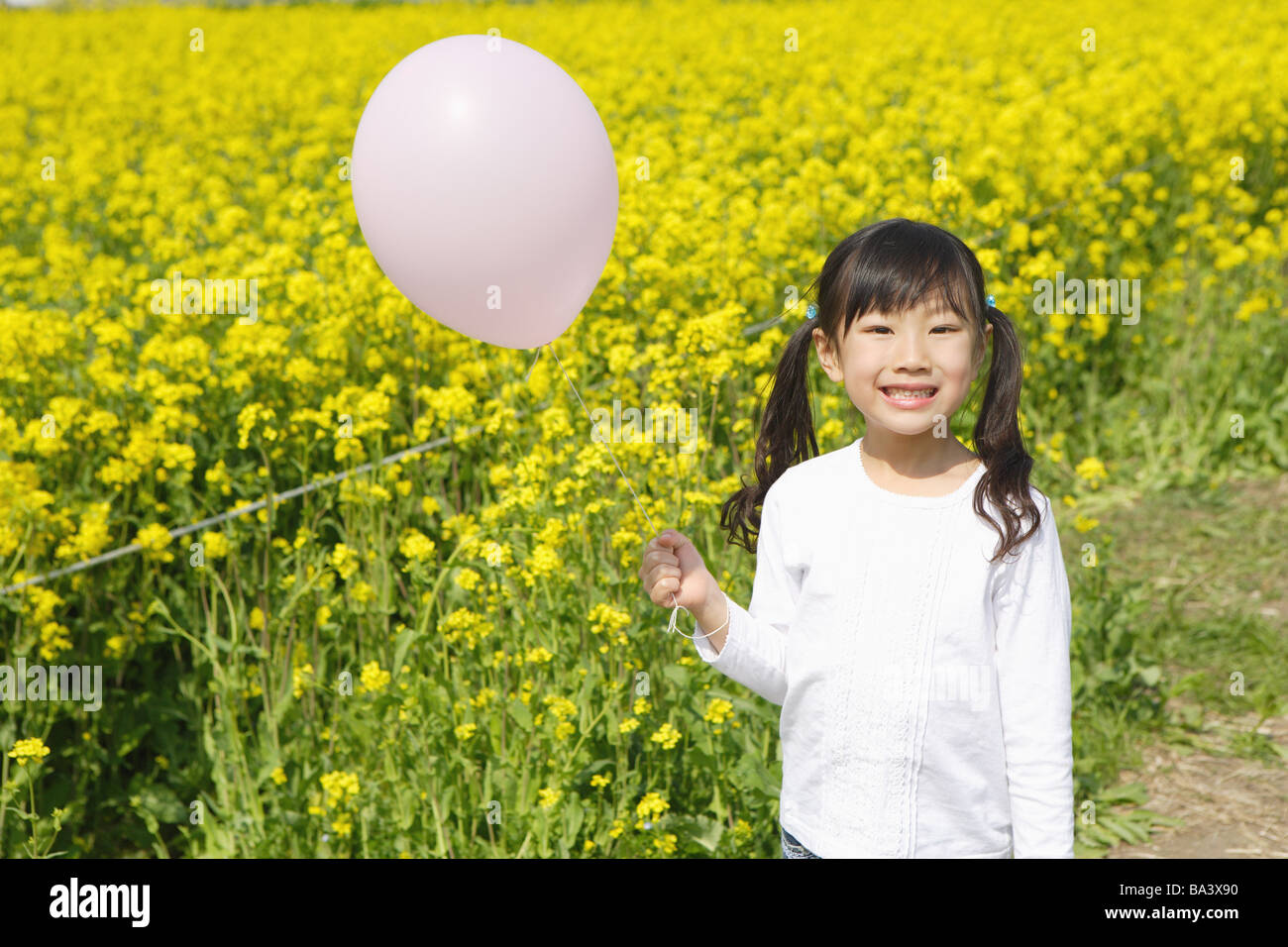 Mädchen mit Ballon in Senf Blumen Stockfoto