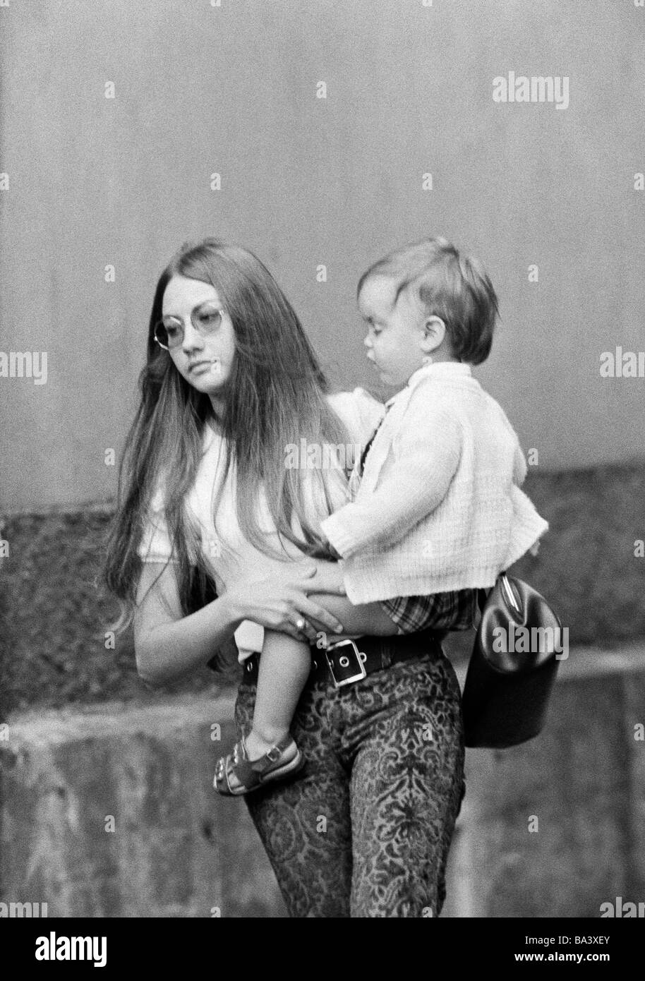 70er Jahre, schwarz / weiß Foto, Menschen, Mutter trägt ein Kind in ihren Armen, im Alter von 25 bis 30 Jahren, Mädchen, im Alter von 2 bis 3 Jahre Stockfoto