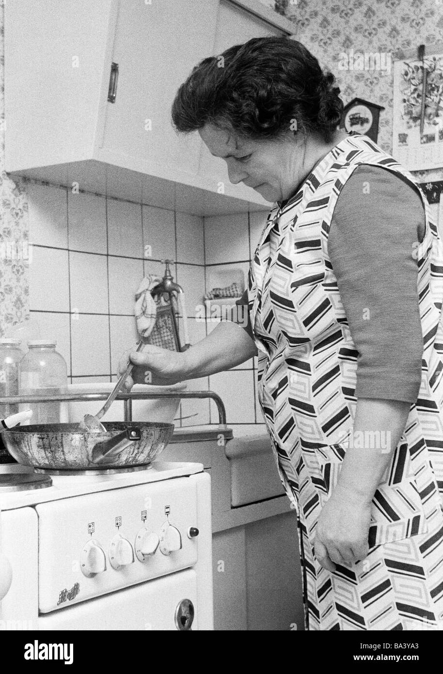 70er Jahre, schwarz / weiß Foto, Menschen, ältere Frau steht auf dem Herd kochen und bereitet das Essen, im Alter von 55 bis 65 Jahren, Katharina Stockfoto