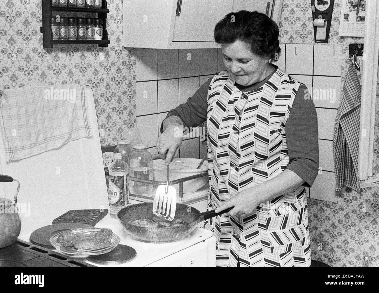 70er Jahre, schwarz / weiß Foto, Menschen, ältere Frau steht auf dem Herd kochen und bereitet das Essen, im Alter von 55 bis 65 Jahren, Katharina Stockfoto